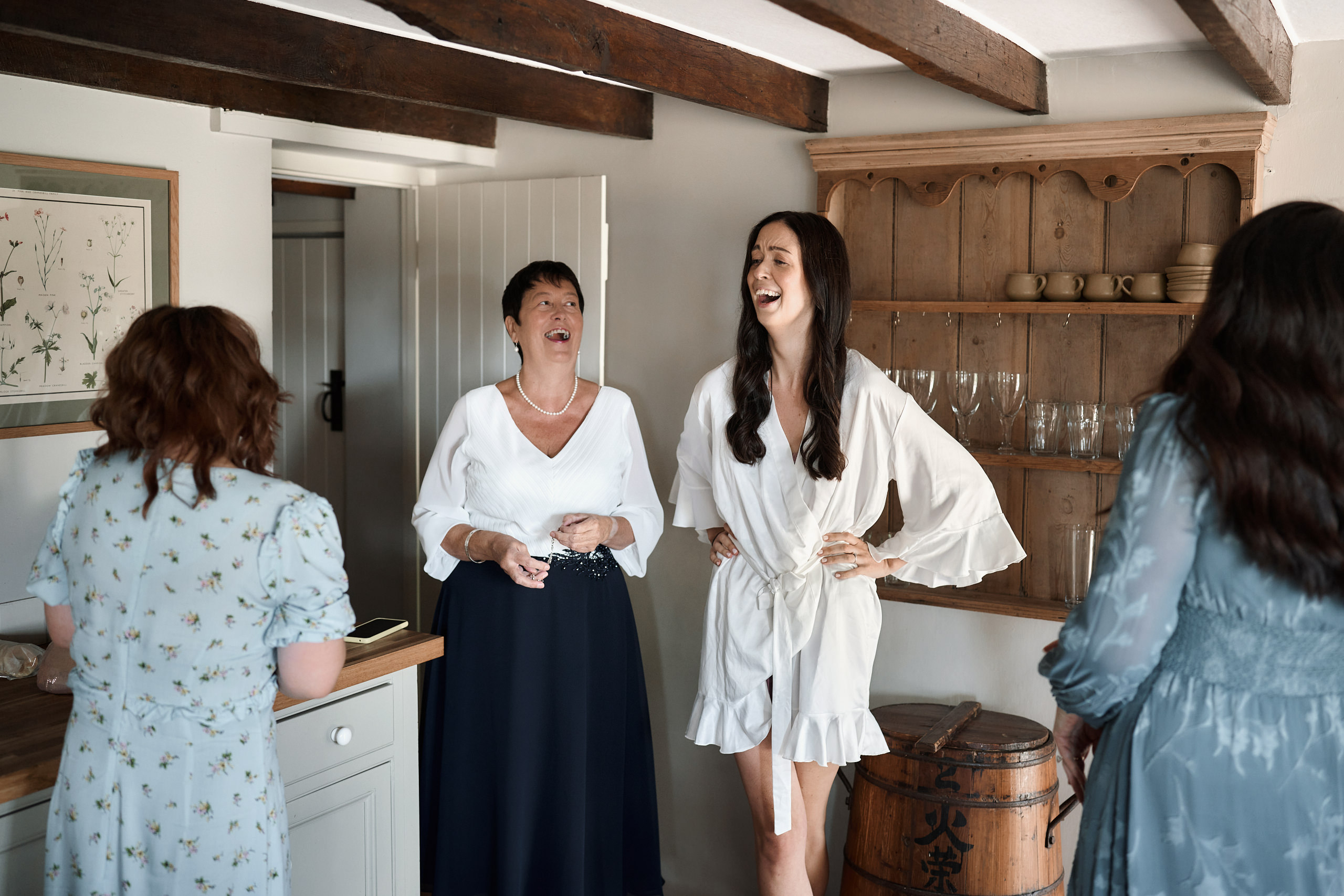 The bride and her friends are chilling out and having a good time in the kitchen.