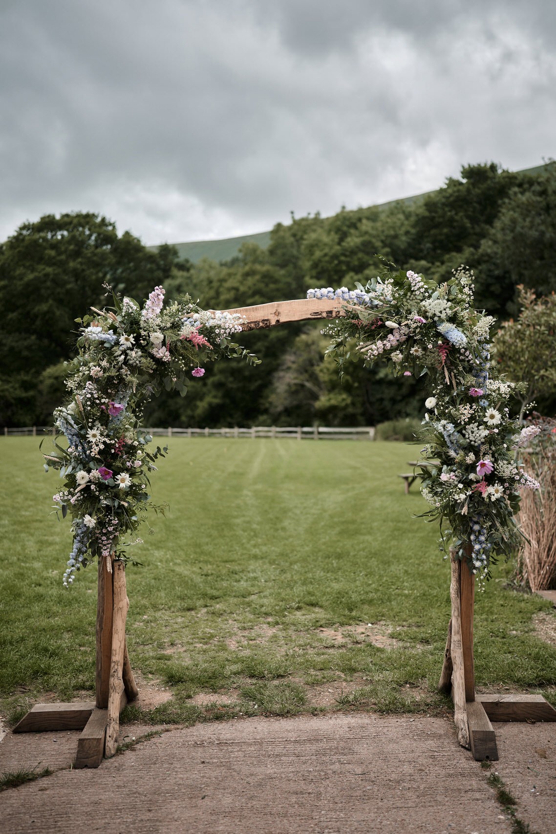 A wedding arch made of wood in a field full of flowers.