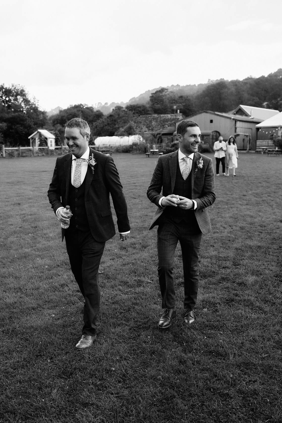 Two guys in formal outfits are strolling through a field.