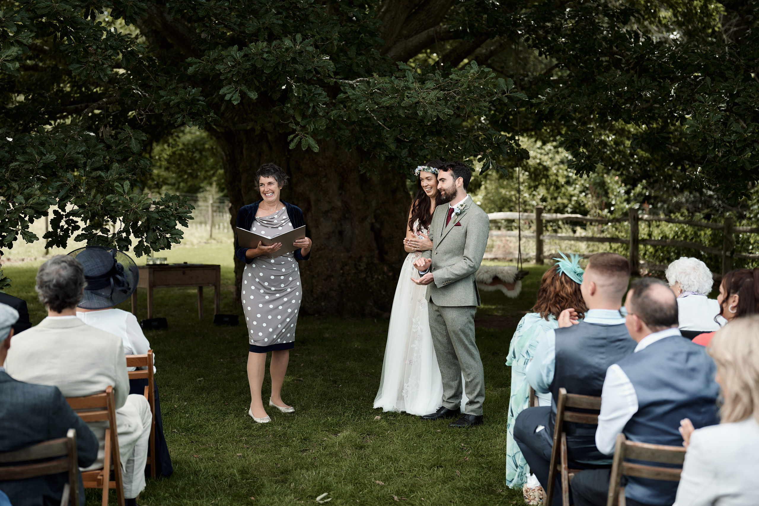 A couple getting married is standing under a tree during their wedding.