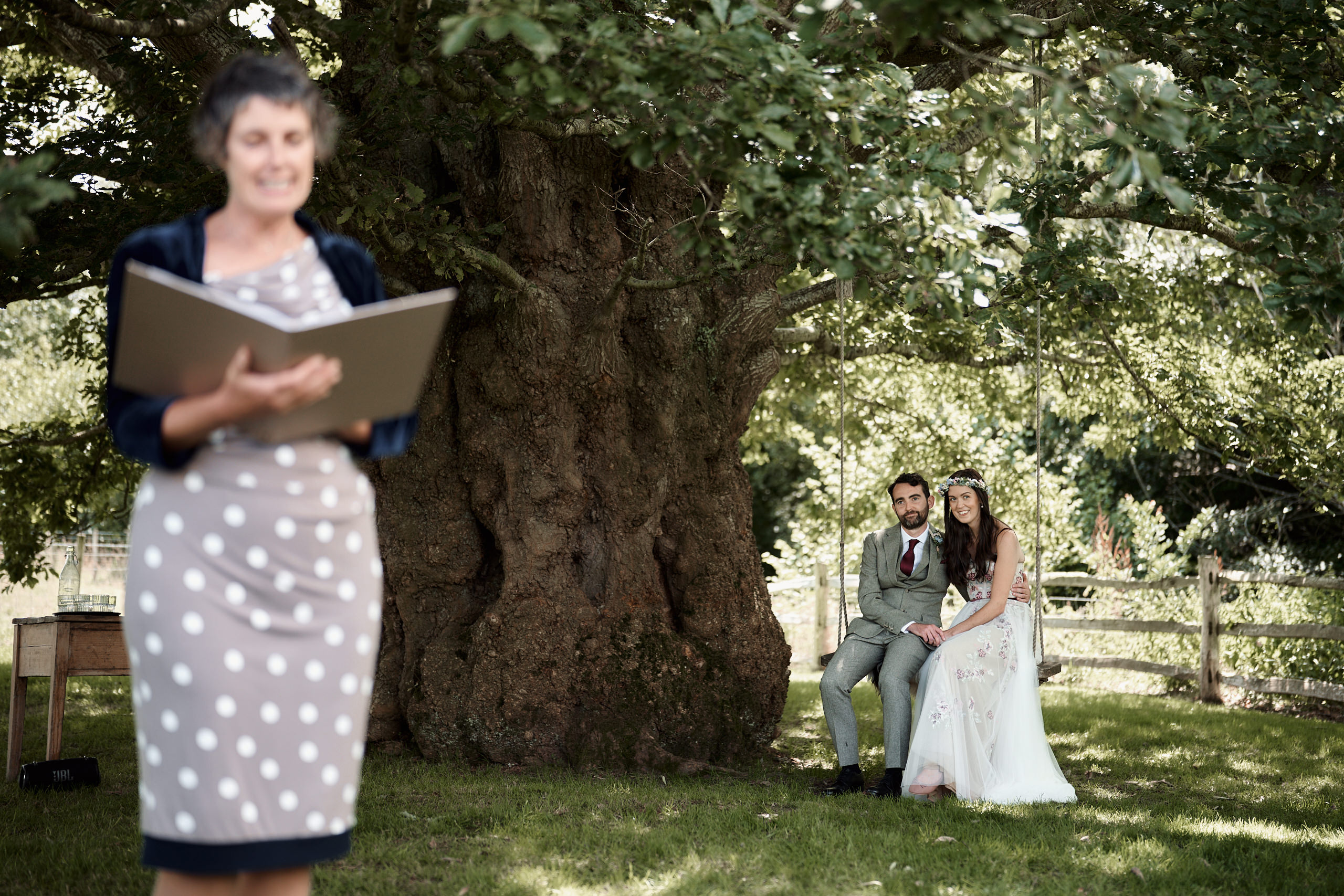 A couple is reading their marriage promises to each other by a tree.