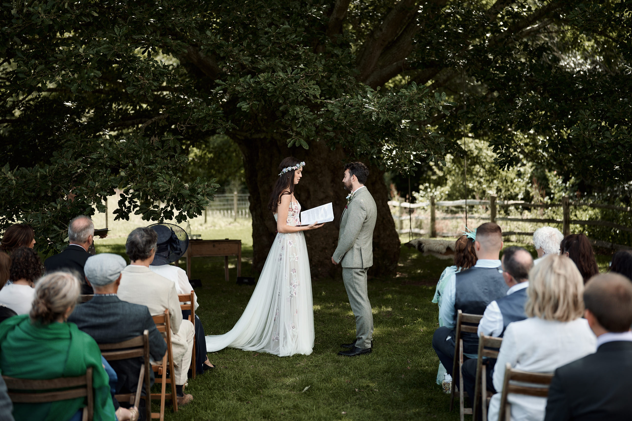 A couple getting married share promises by a tree.