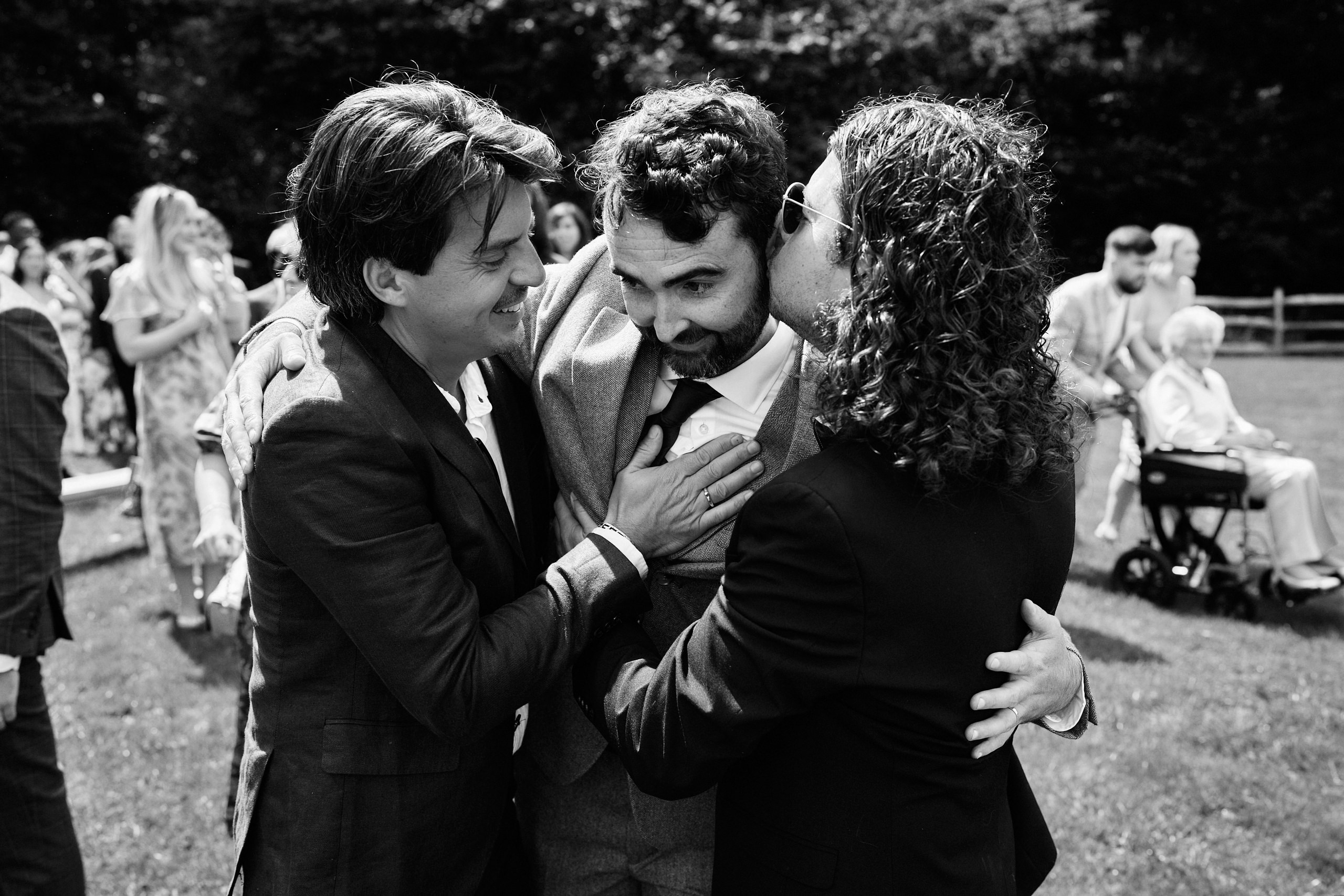 Three guys giving each other a hug at a wedding.