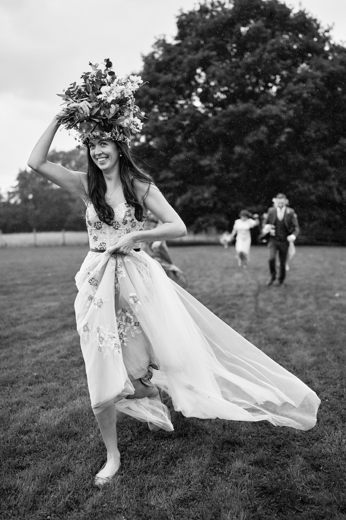 A woman who's just gotten married, sprinting across a meadow wearing a wreath of flowers in her hair.