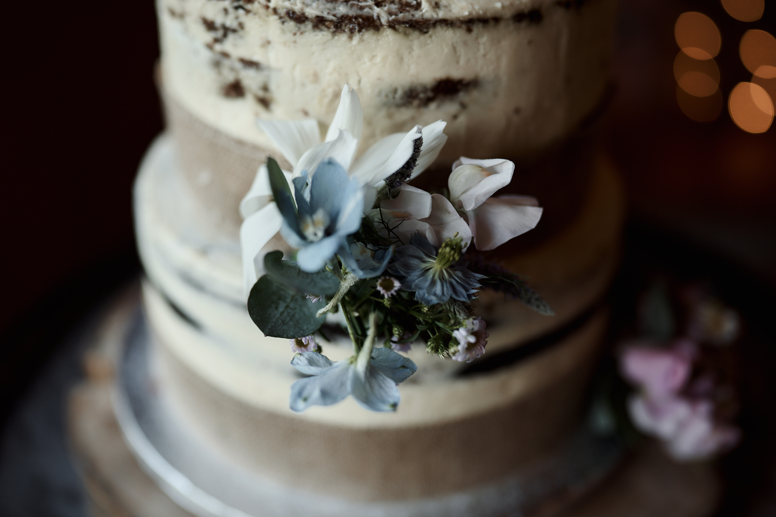 A three-layer wedding cake topped with flowers.