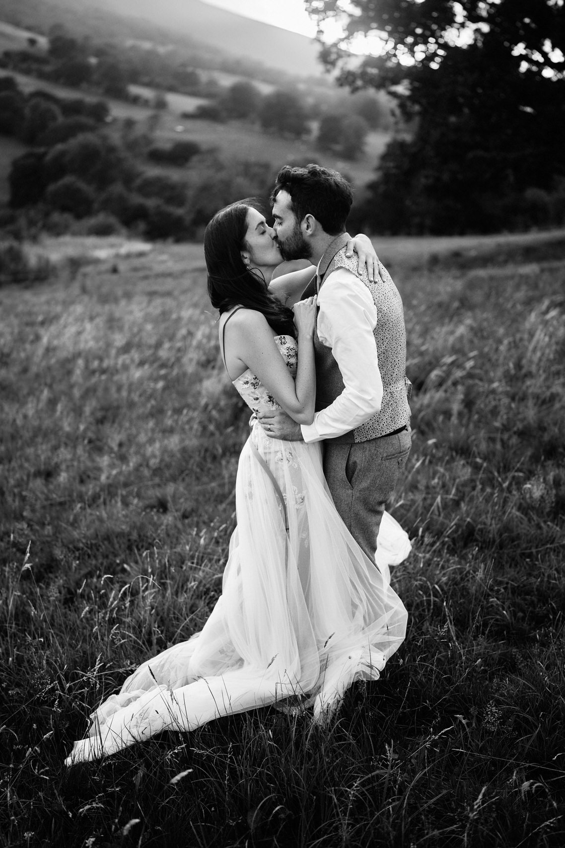 A couple getting married is smooching in a field.
