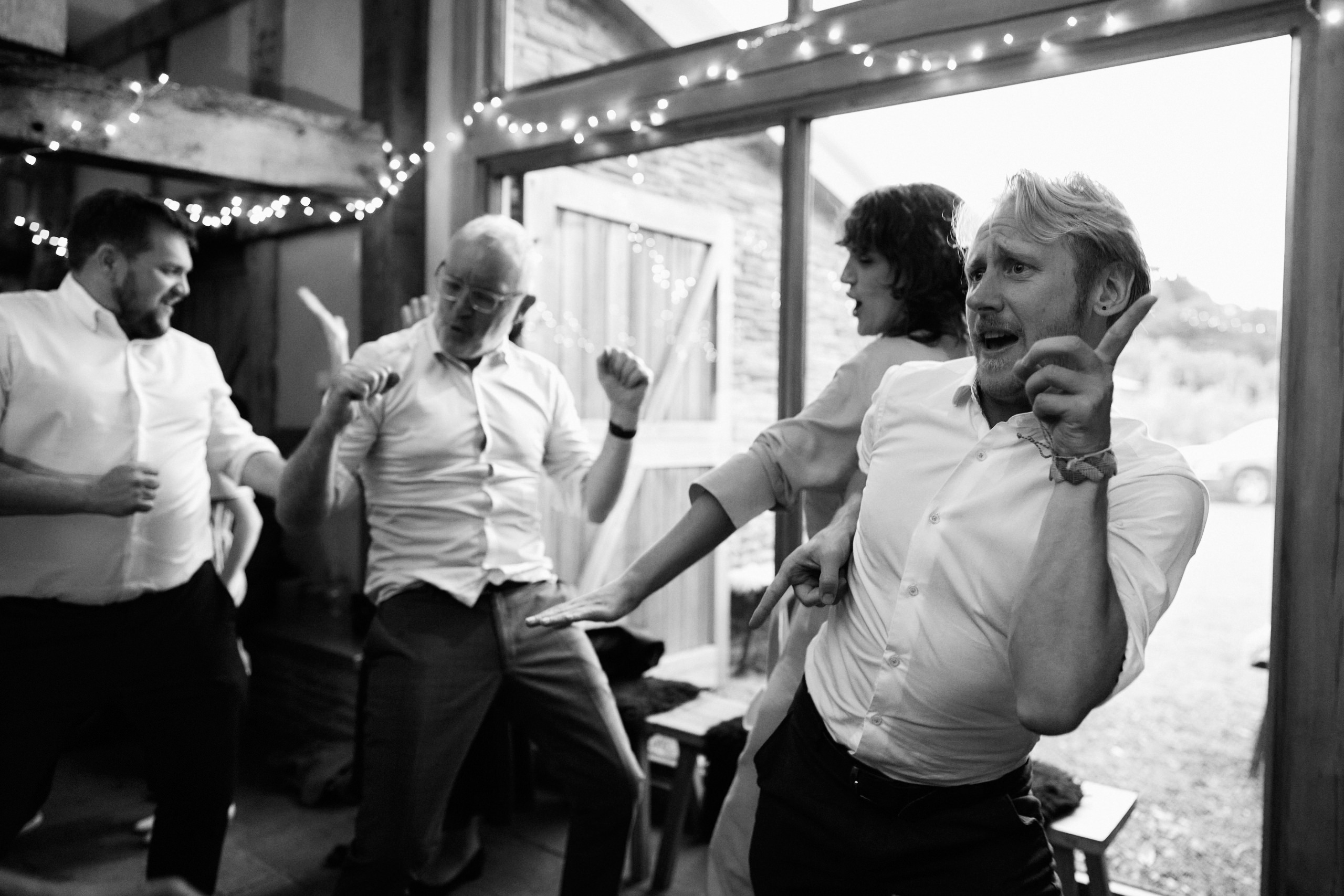 A group of people are dancing in a barn in this black and white picture.