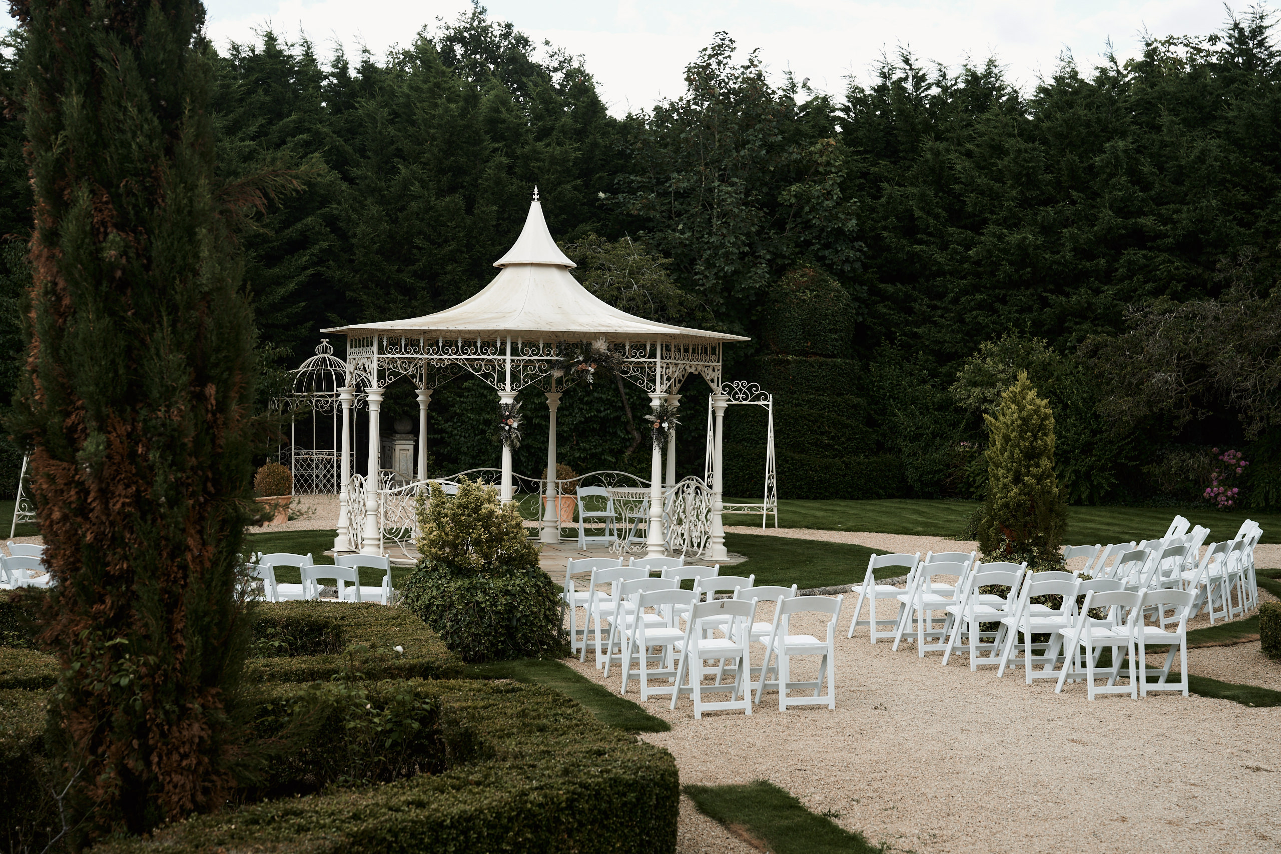 A wedding scene with white seats and a small outdoor structure.