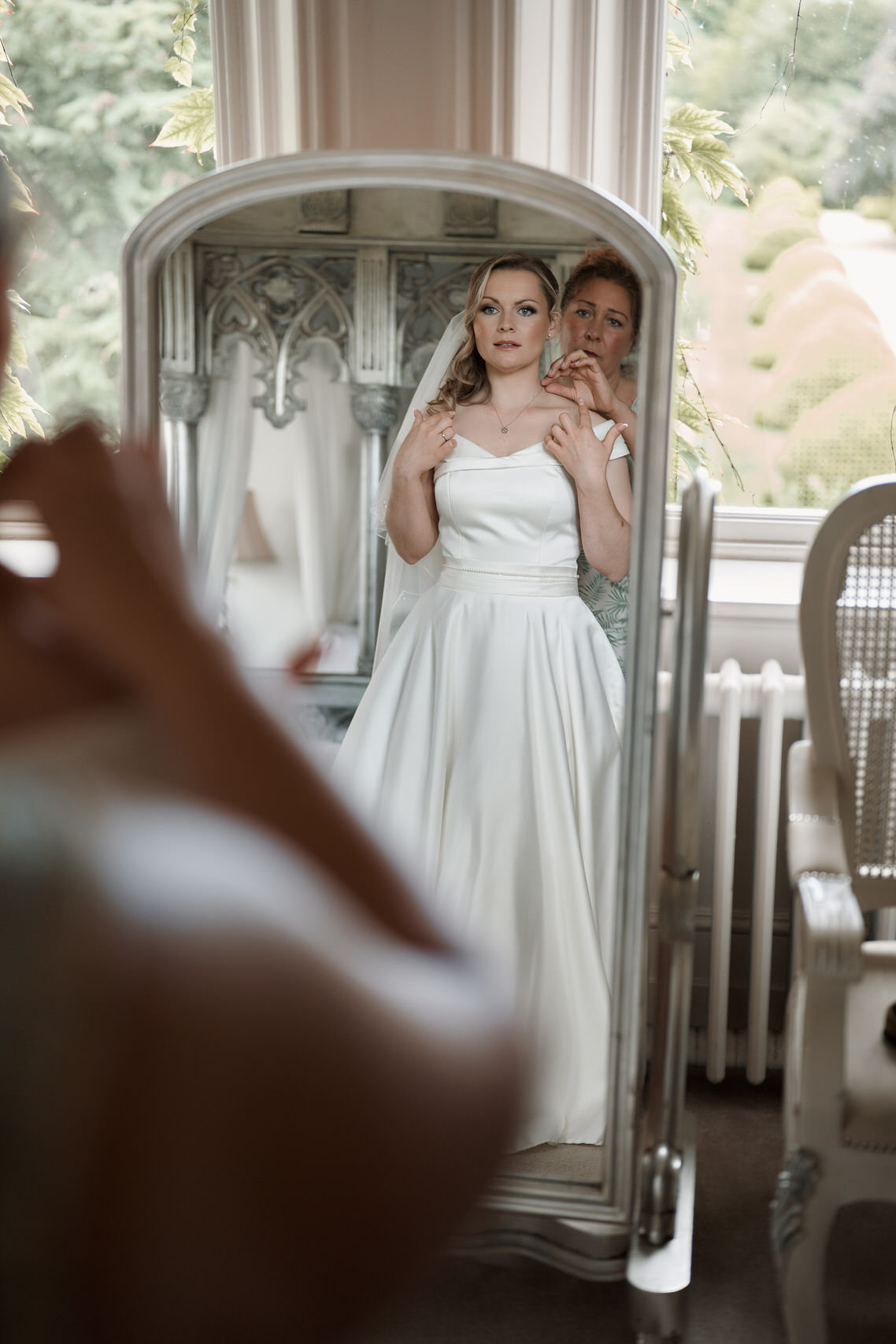 A woman is getting into her wedding dress in front of a mirror.