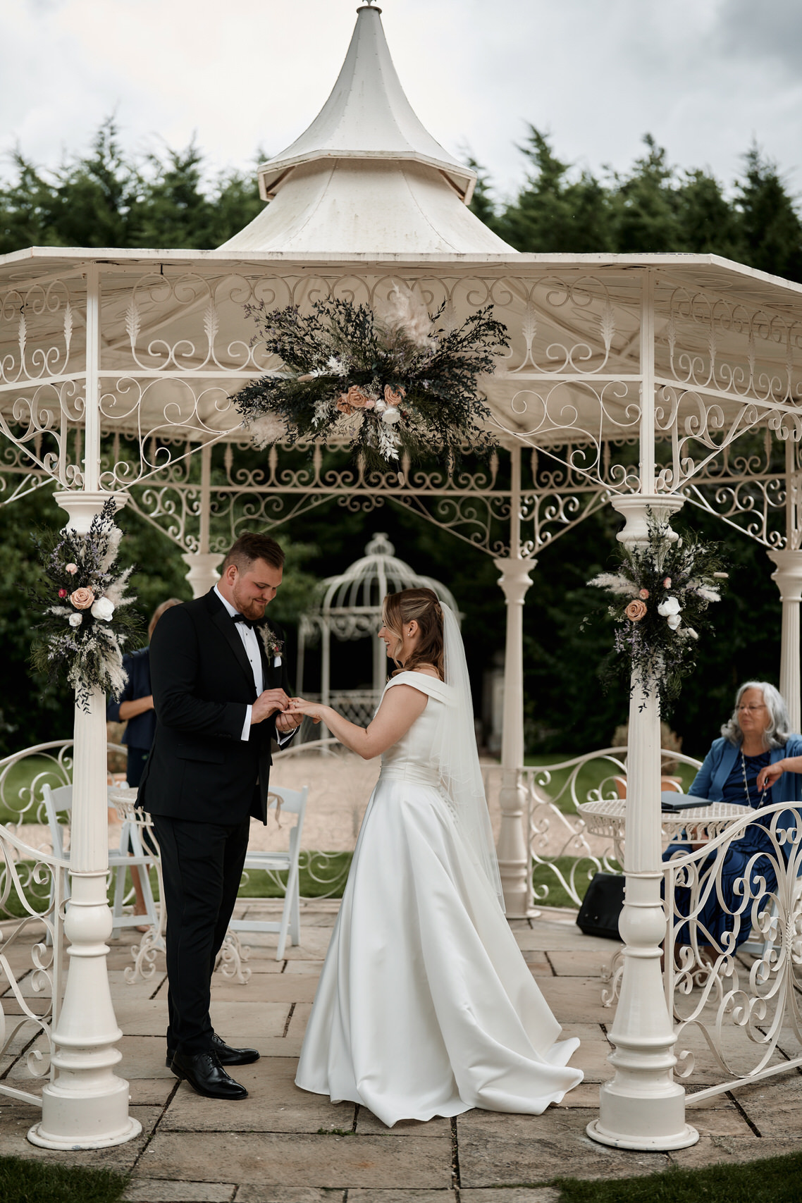 A couple getting married say their promises to each other in a pavilion.