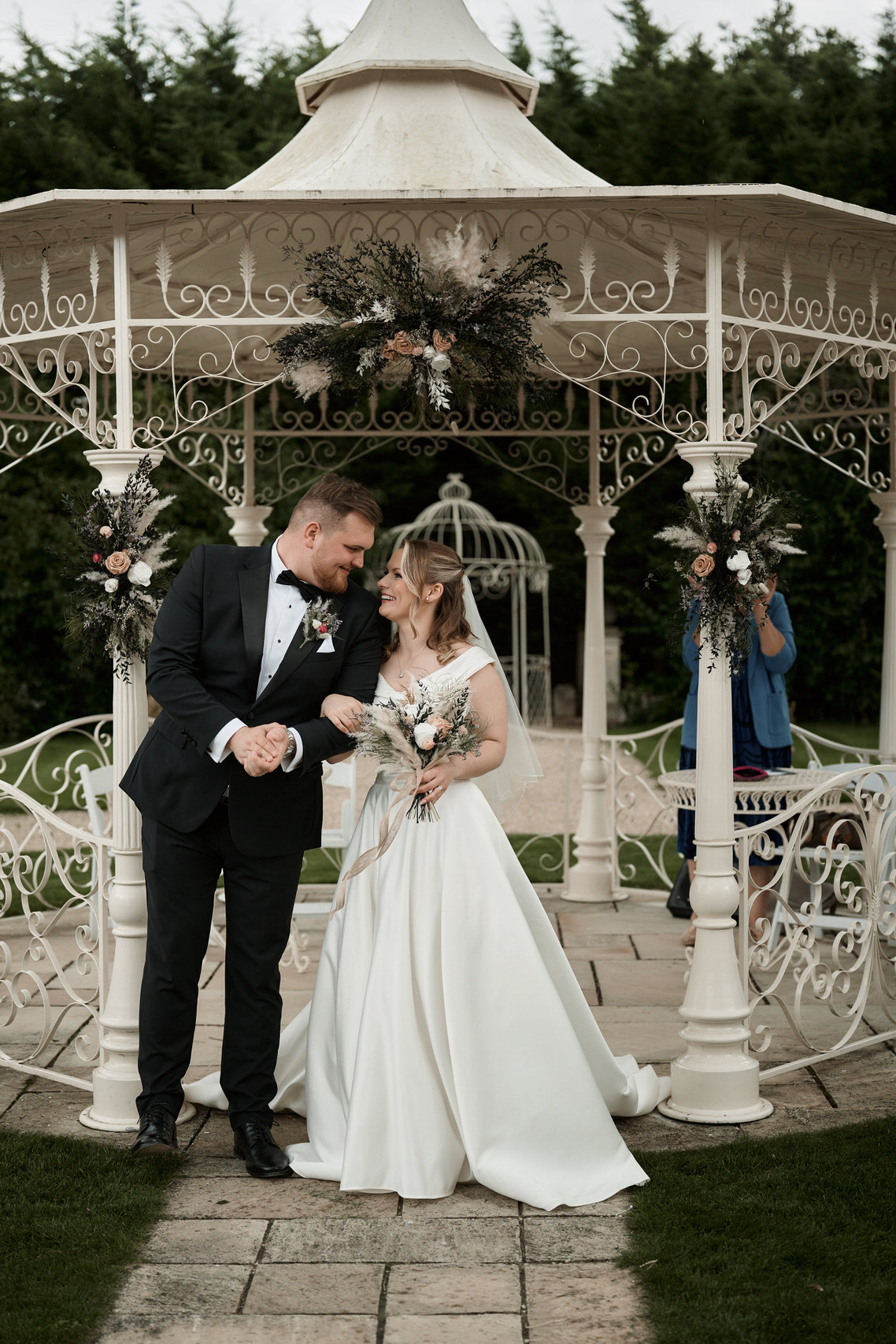 A couple getting married standing under a small outdoor structure.