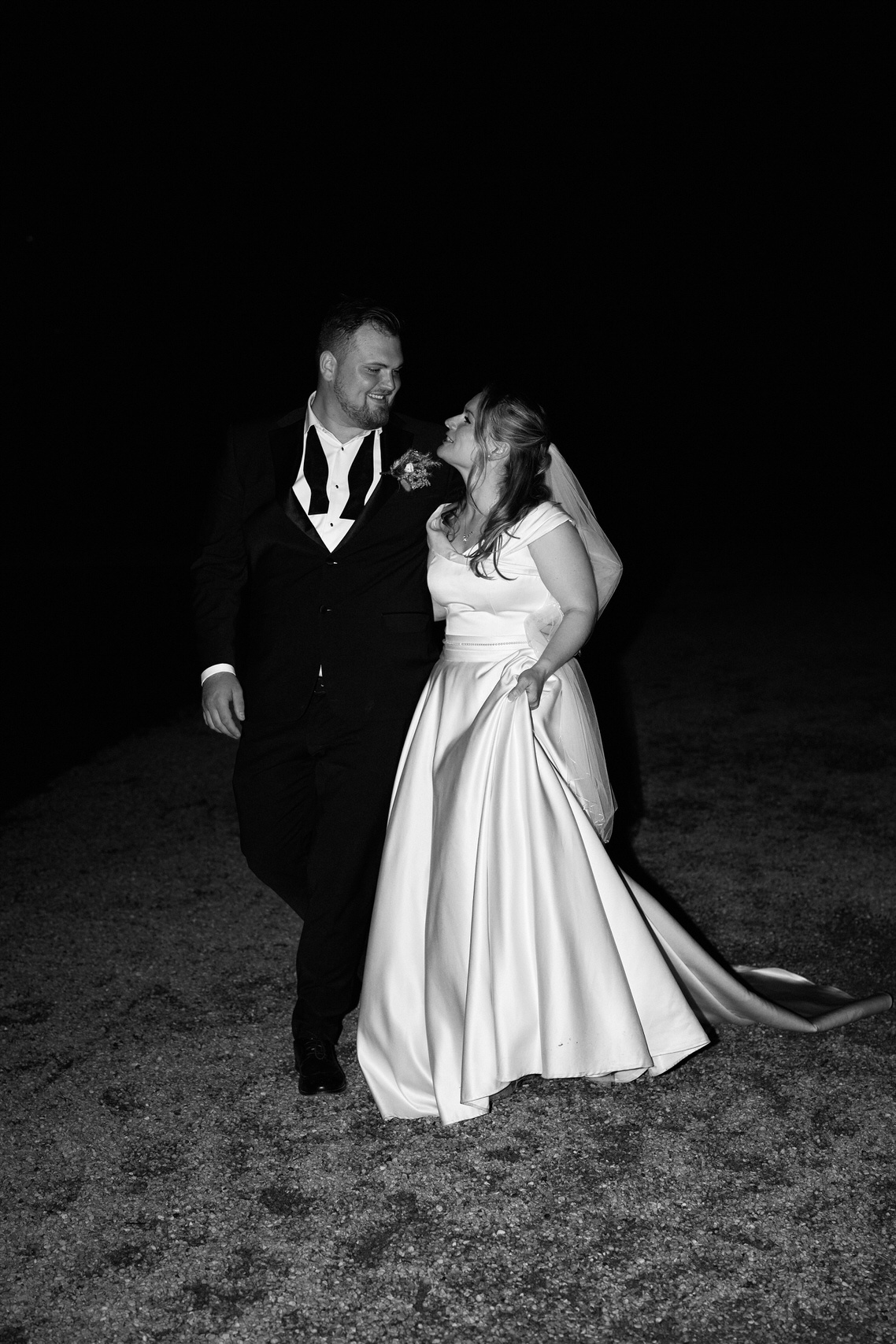 A married couple is standing in a field at night.