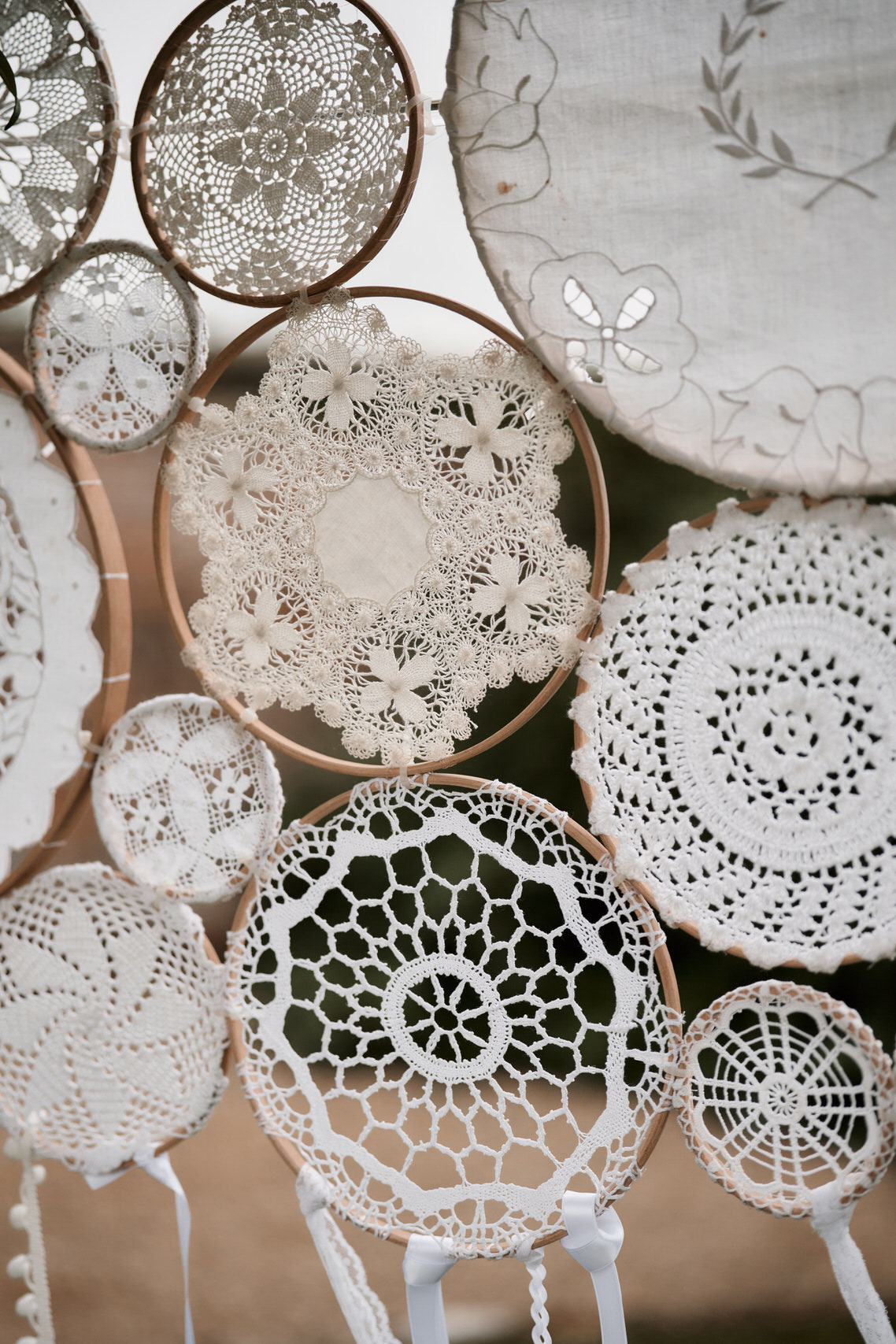 Some lace table mats are hanging from a tree.
