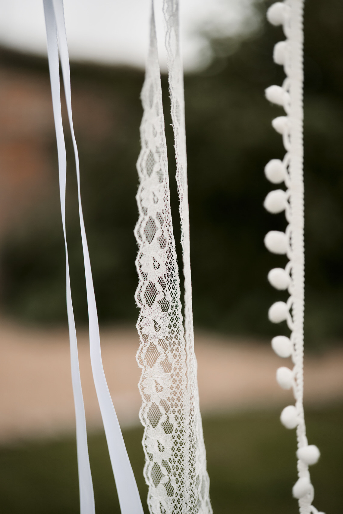 White lace and ribbons are dangling from a tree.