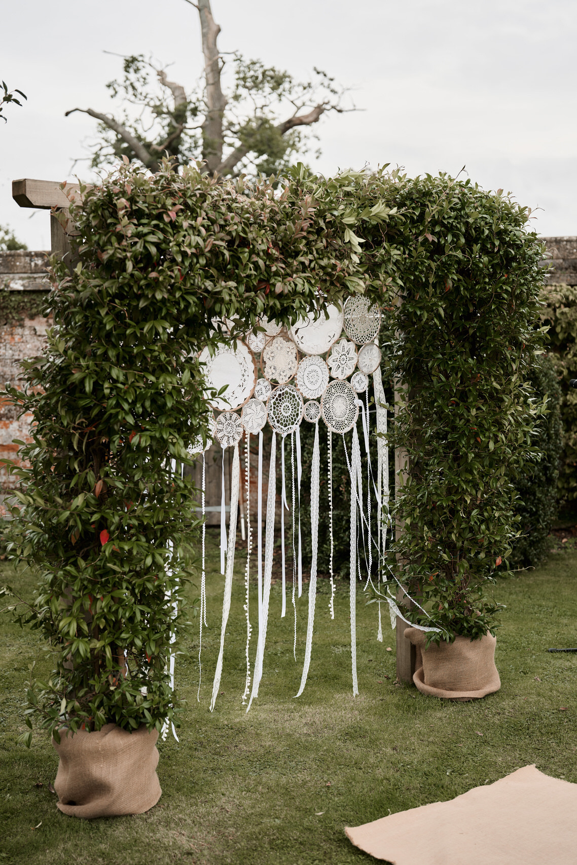 A wedding arch is adorned with paper plates and plants.