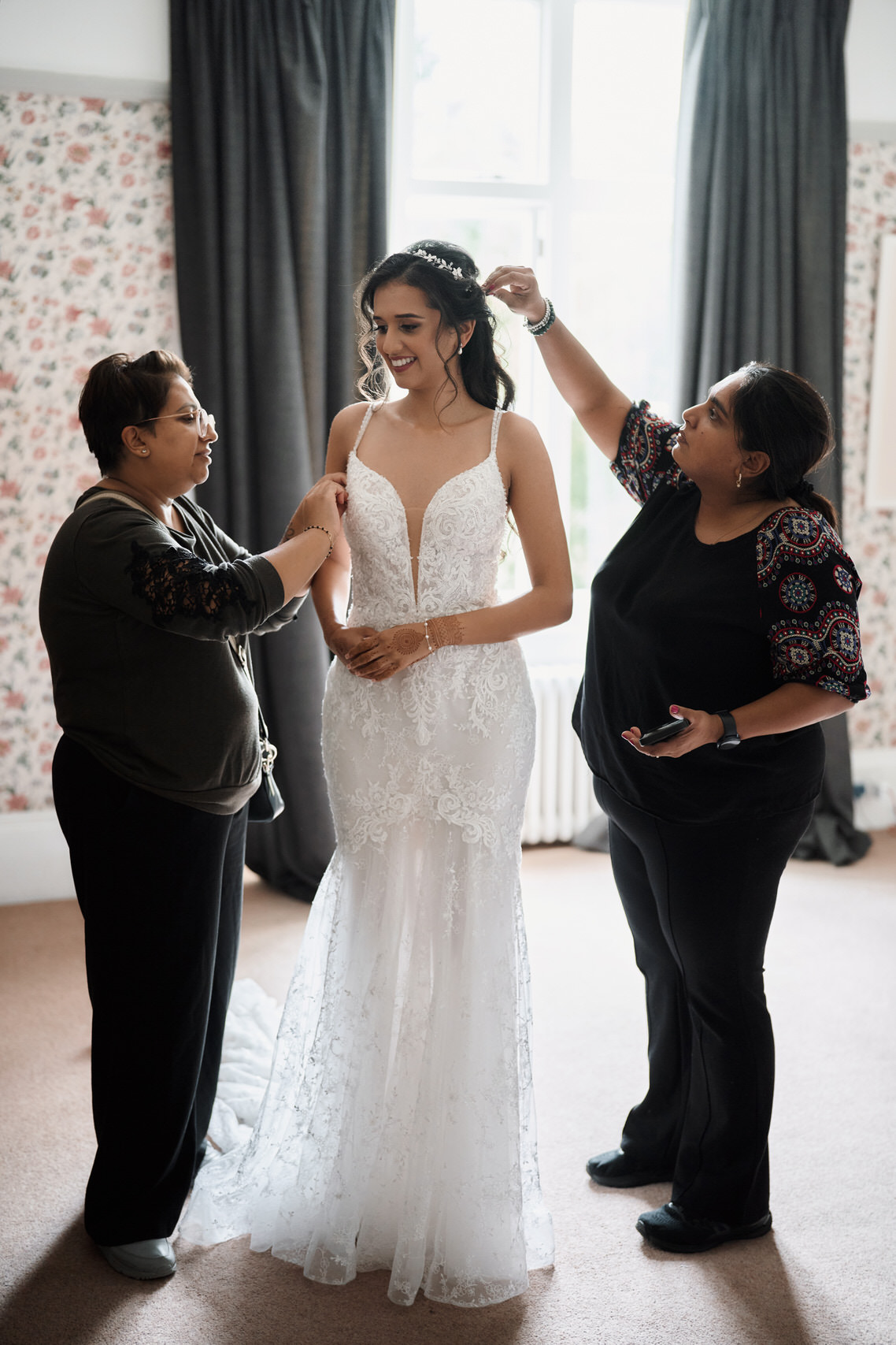 A woman is helping a bride prepare in a room.