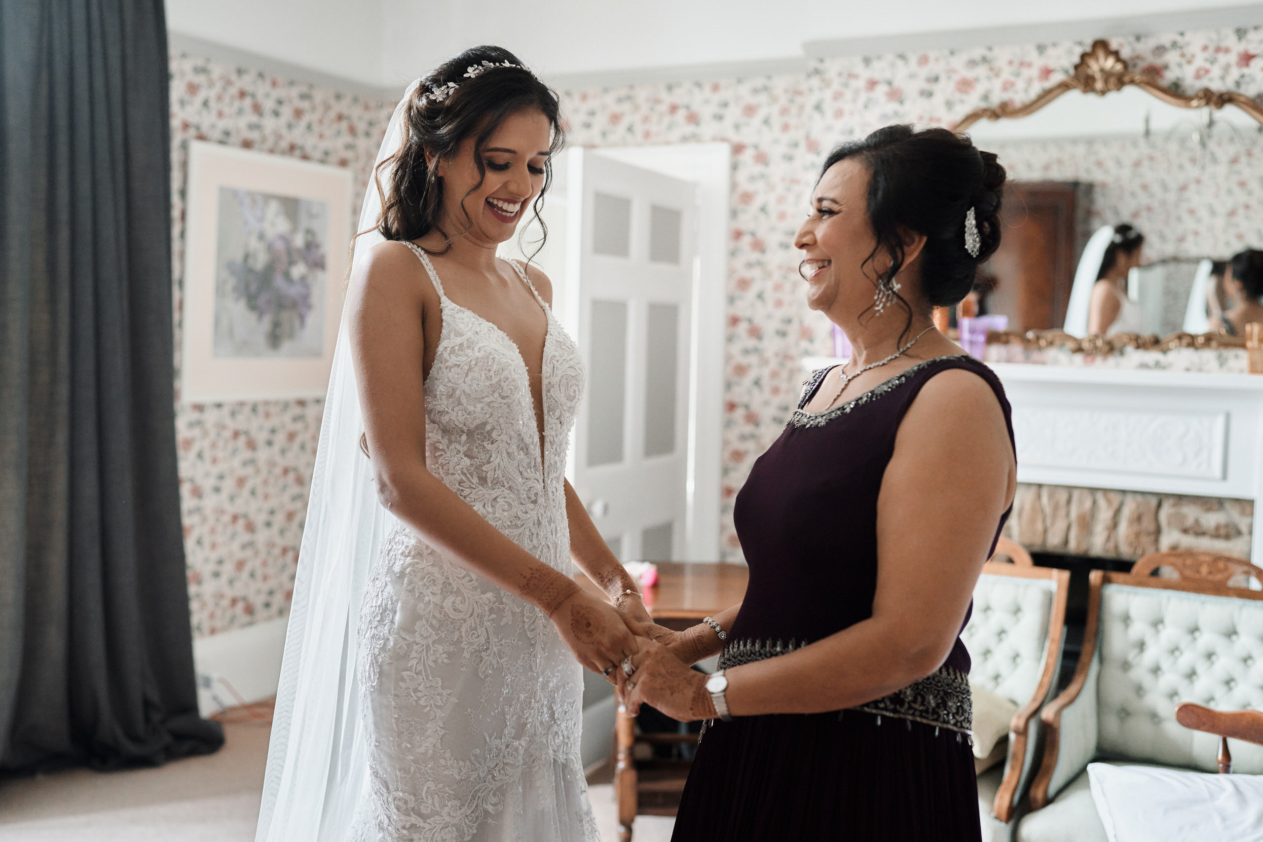 A bride is preparing for her wedding in a room with her mom.