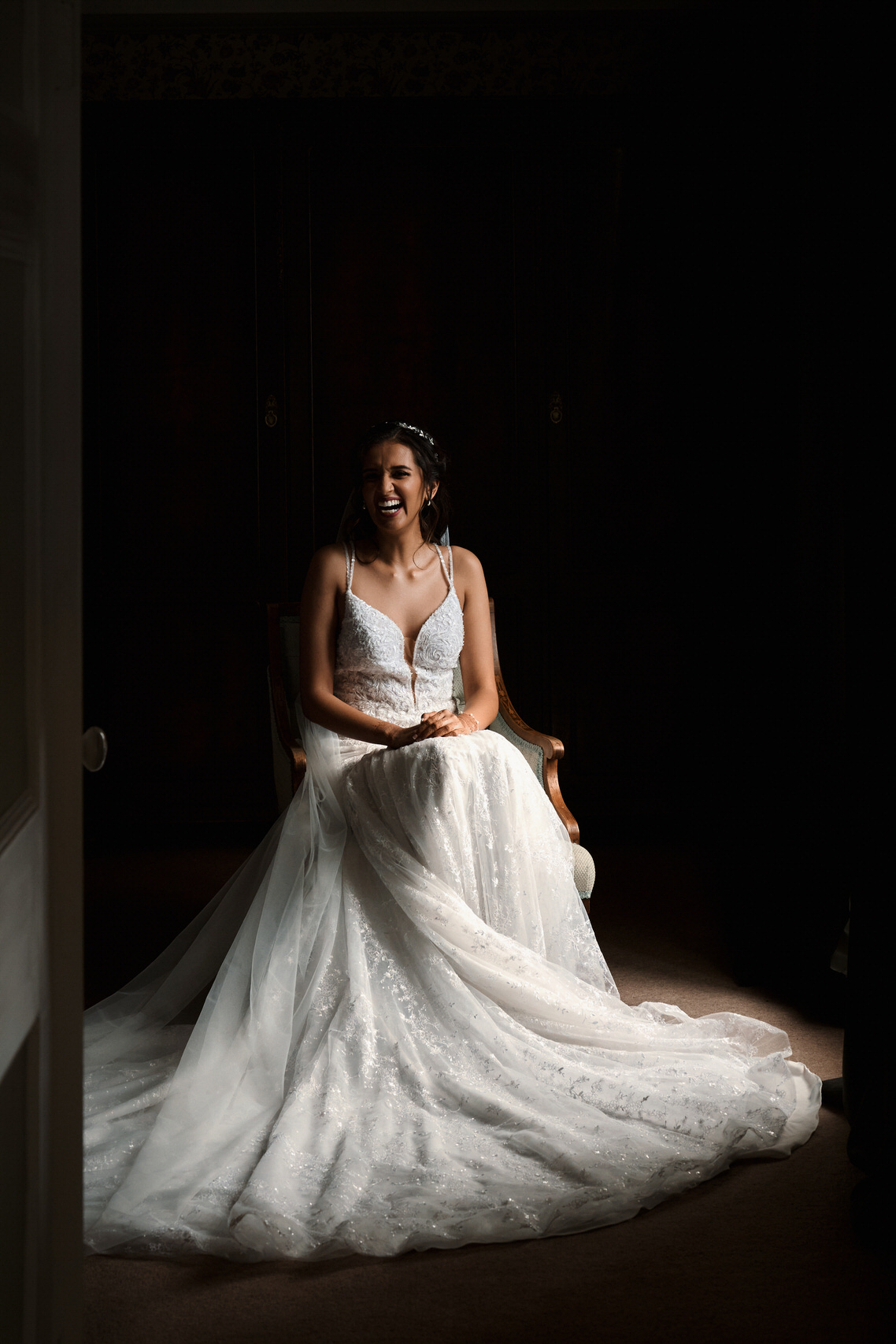 A woman in a wedding dress is sitting in a dimly lit room.