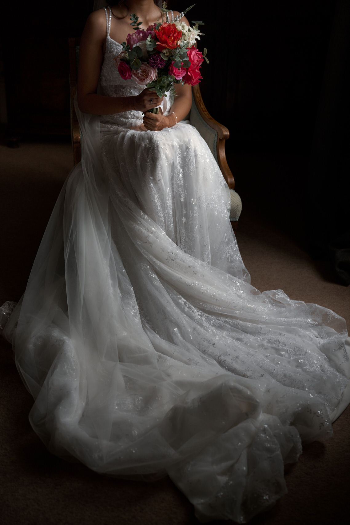 A woman in a wedding dress is sitting and holding flowers.
