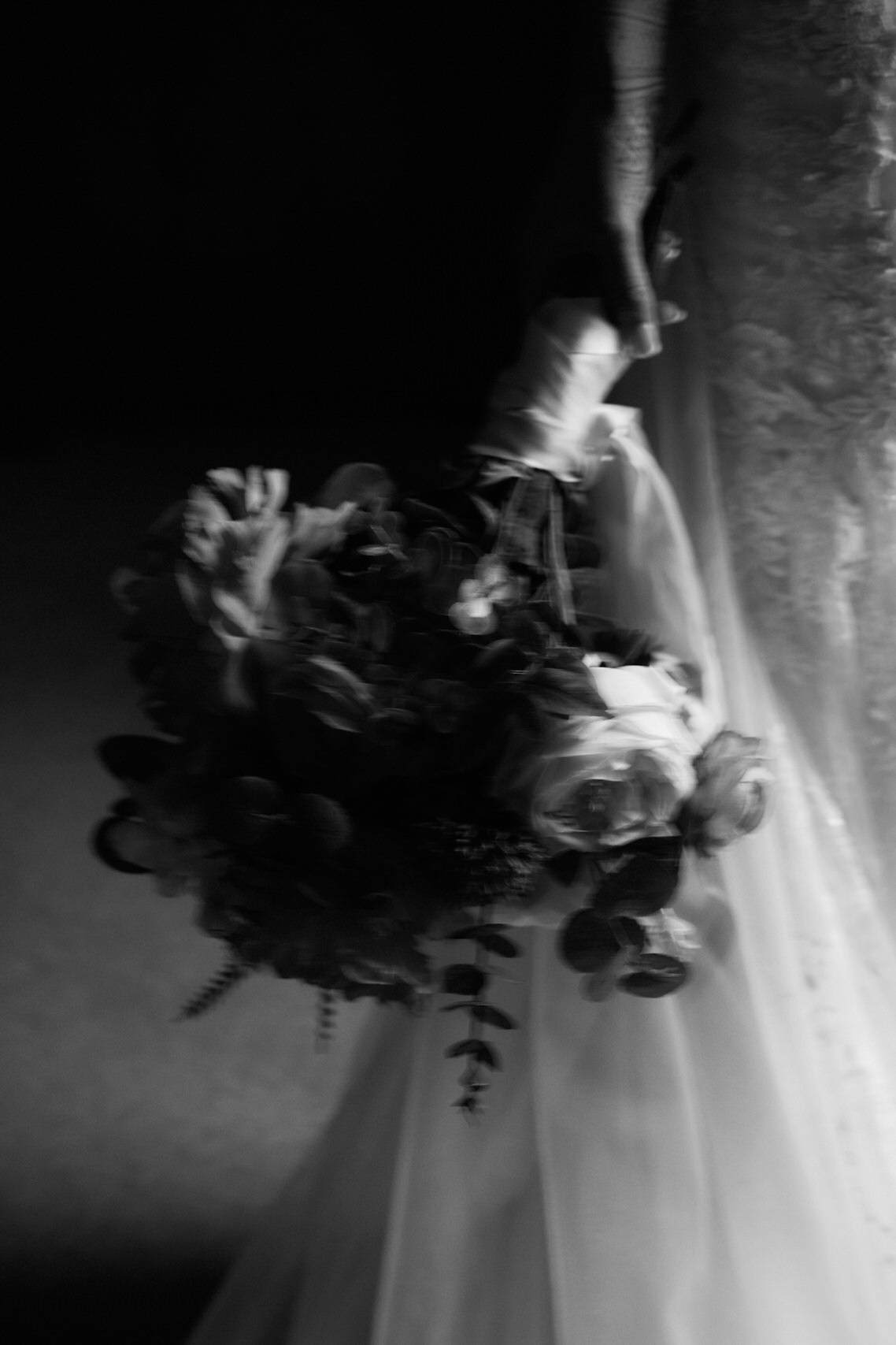 A snapshot in black and white of a bride carrying some flowers.