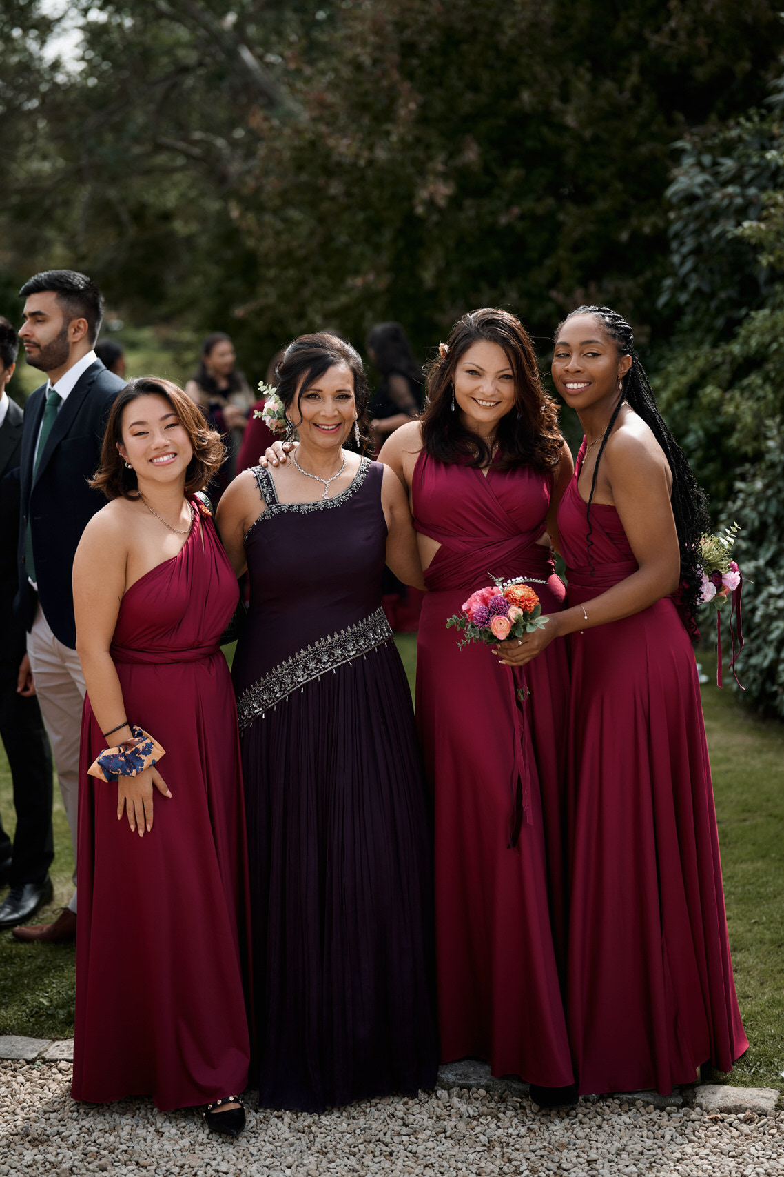 A bunch of bridesmaids in dark red dresses are taking a picture.