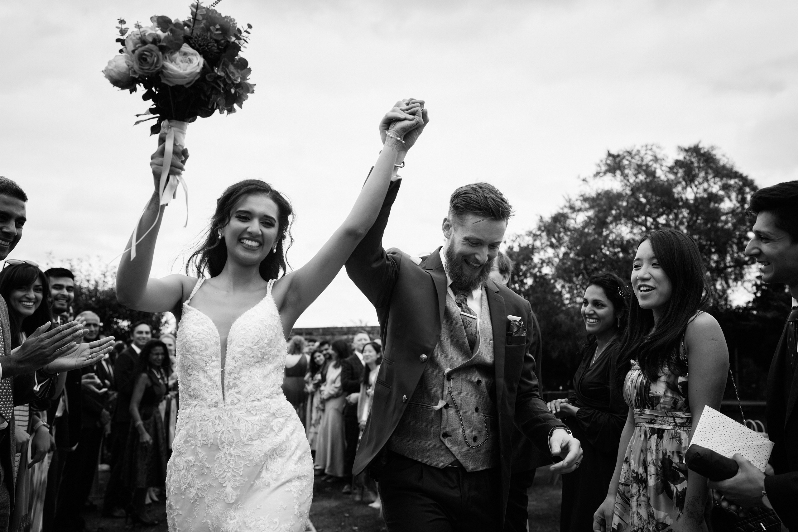 A black and white picture of a couple getting married, walking down the aisle.