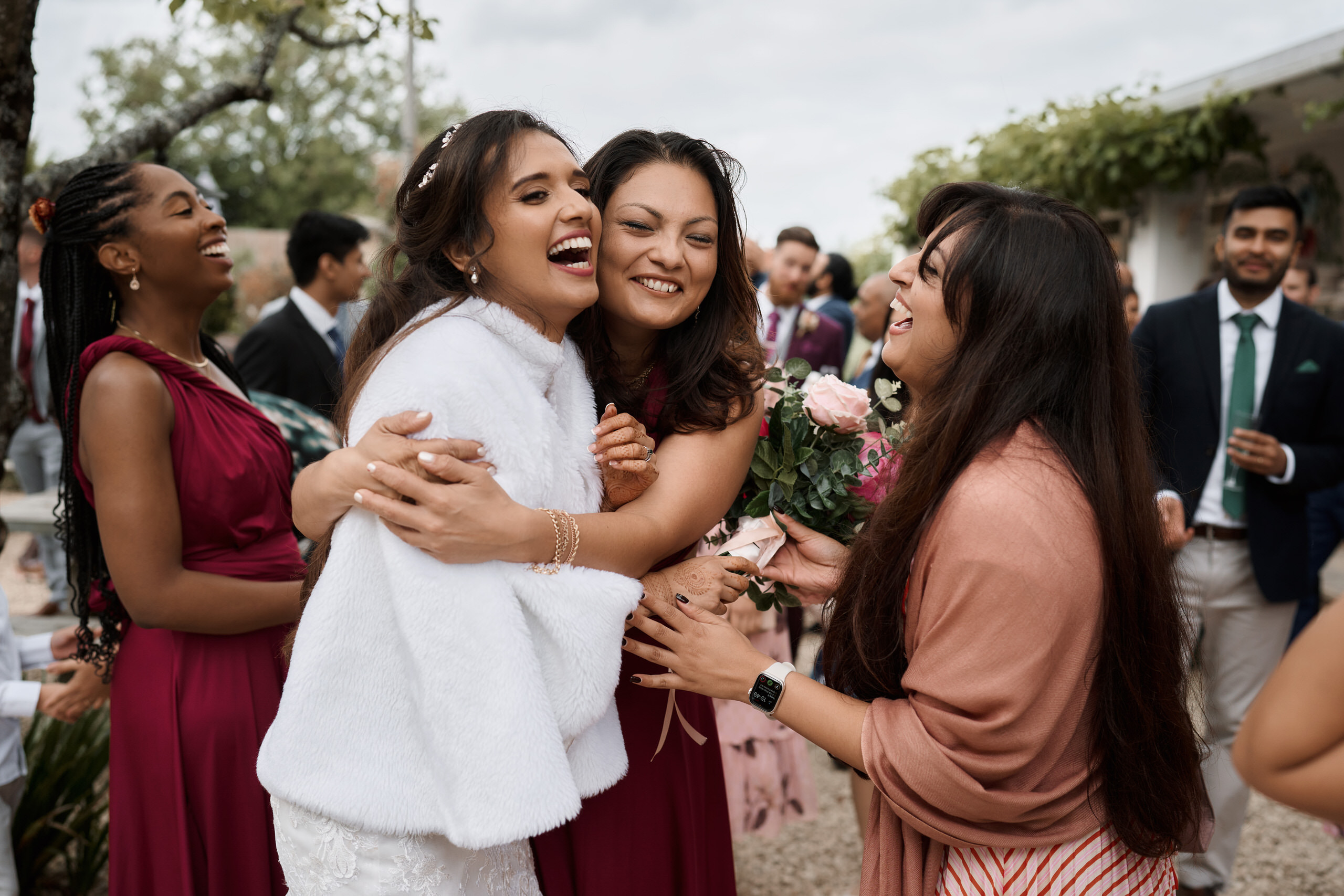 A bunch of bridesmaids are giving each other hugs at a wedding party.
