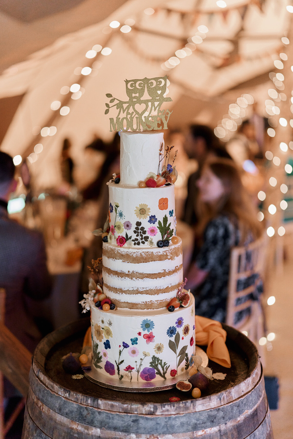 A wedding cake is placed on top of a wooden barrel.