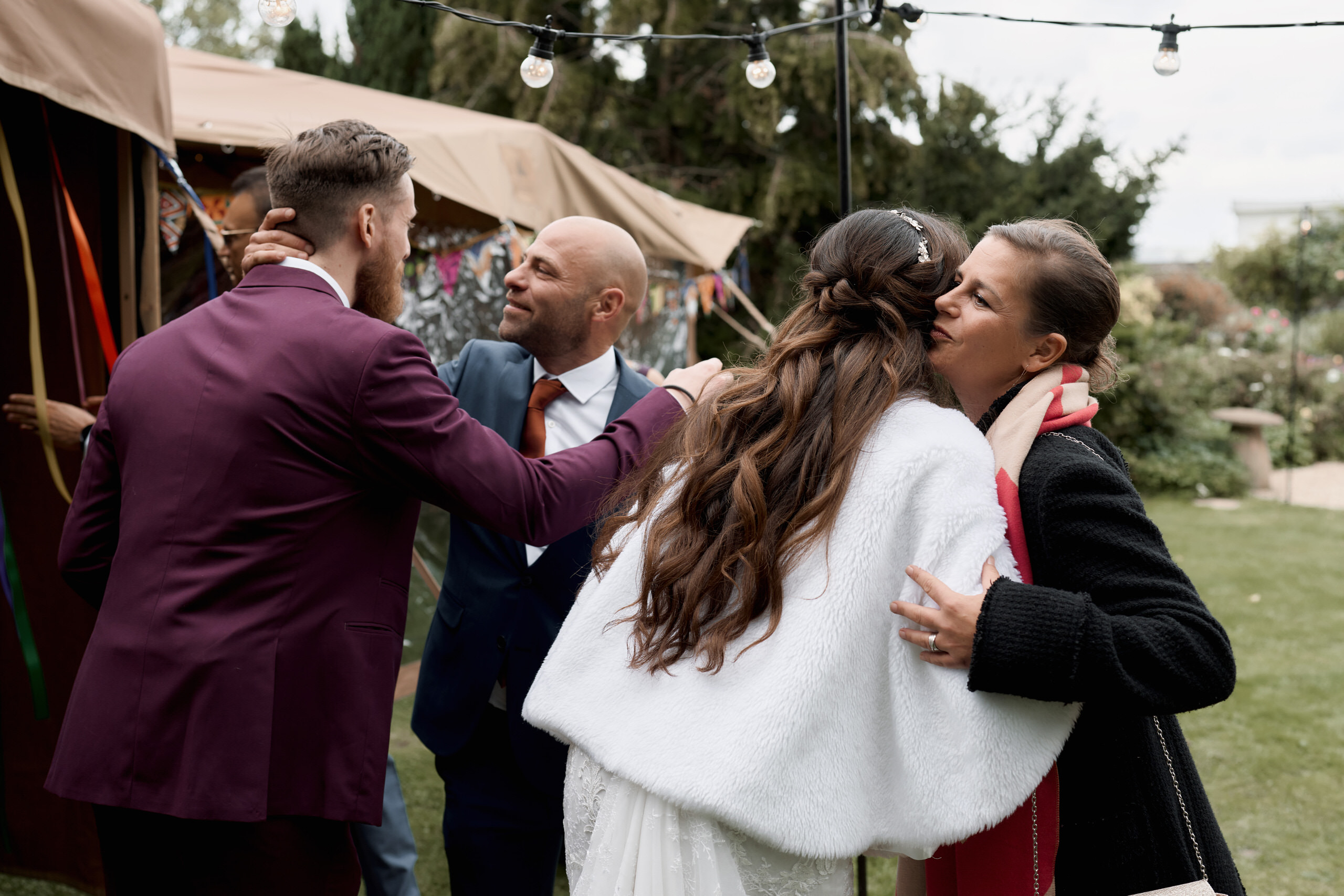 A couple getting married are hugging in front of a tent.