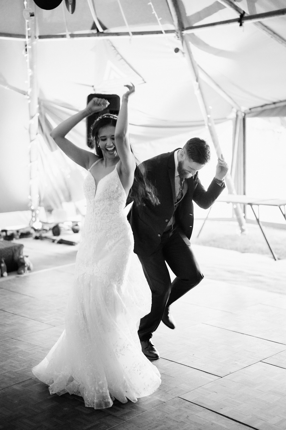A couple is dancing in a tent at their wedding.
