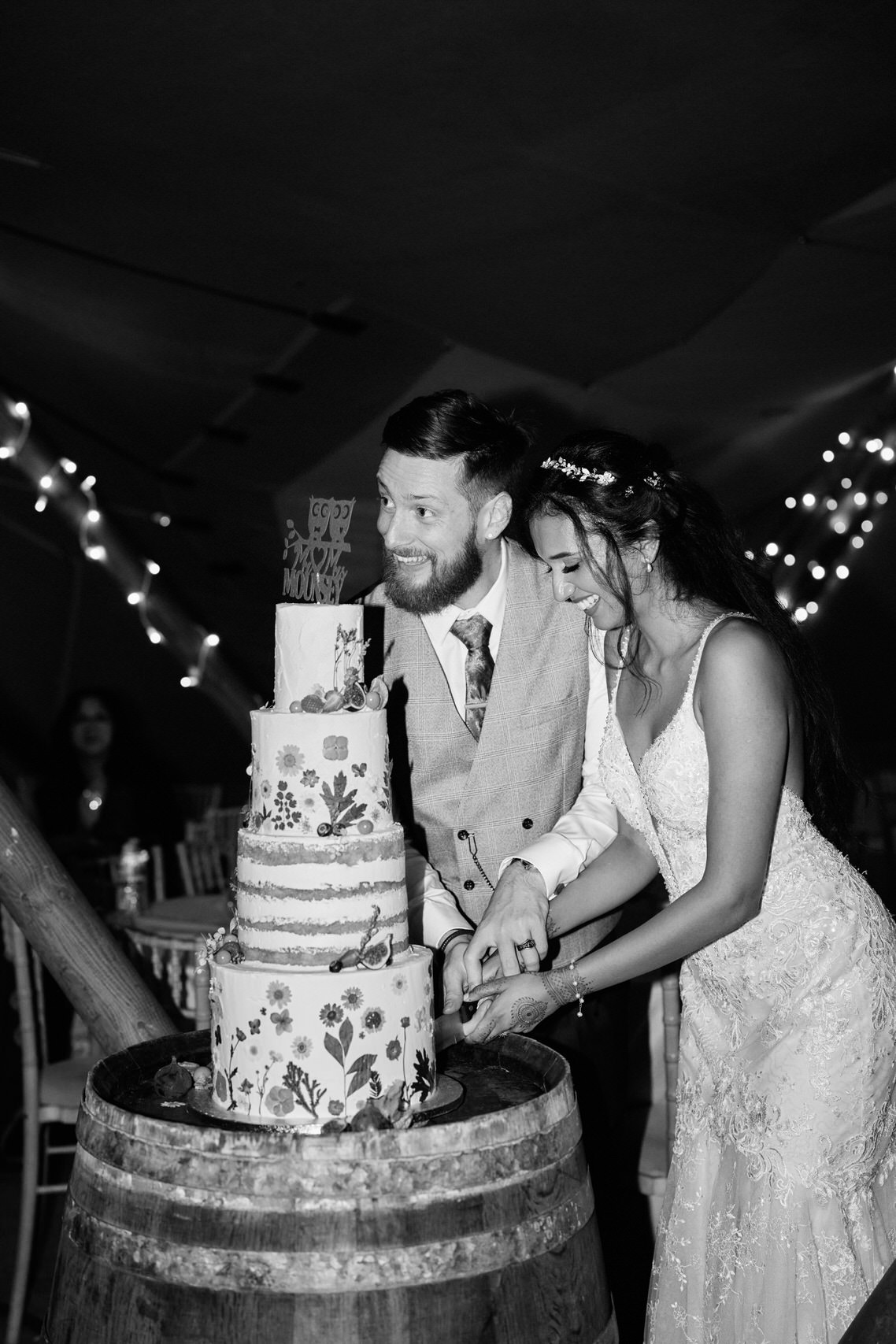 A couple slicing their wedding cake in a barrel.