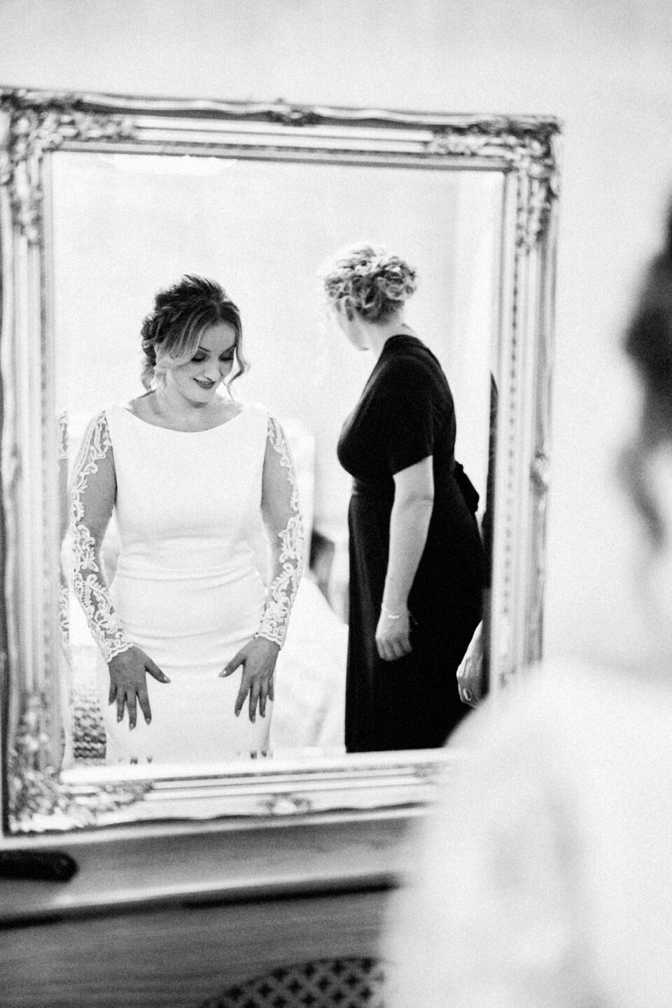 A bride is preparing herself while looking at a mirror.