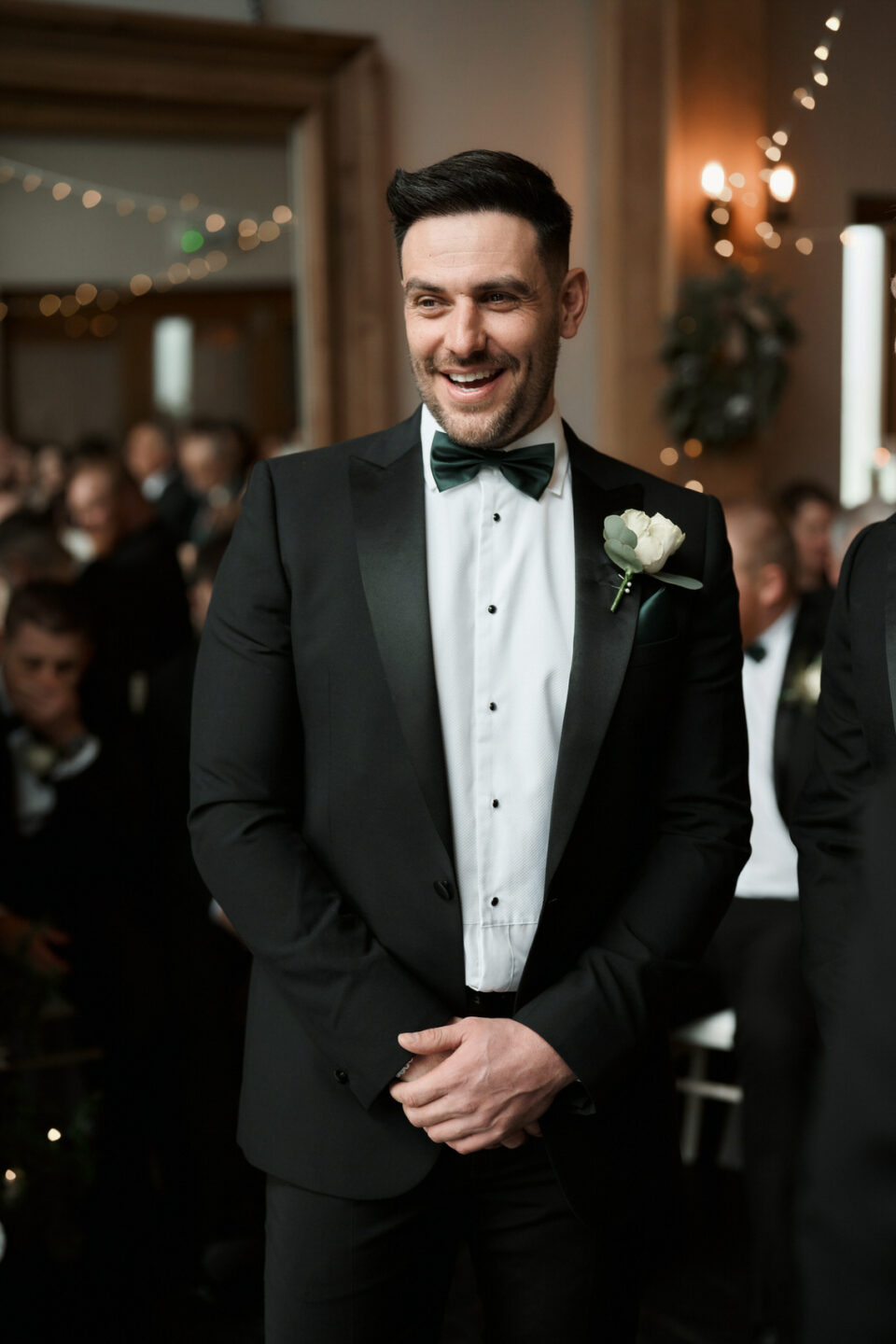 A man dressed in a suit is smiling while walking down the aisle at his wedding.
