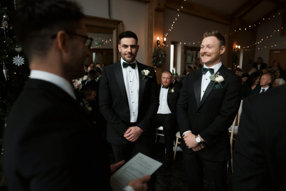Two guys in suits are staring at each other at a wedding.