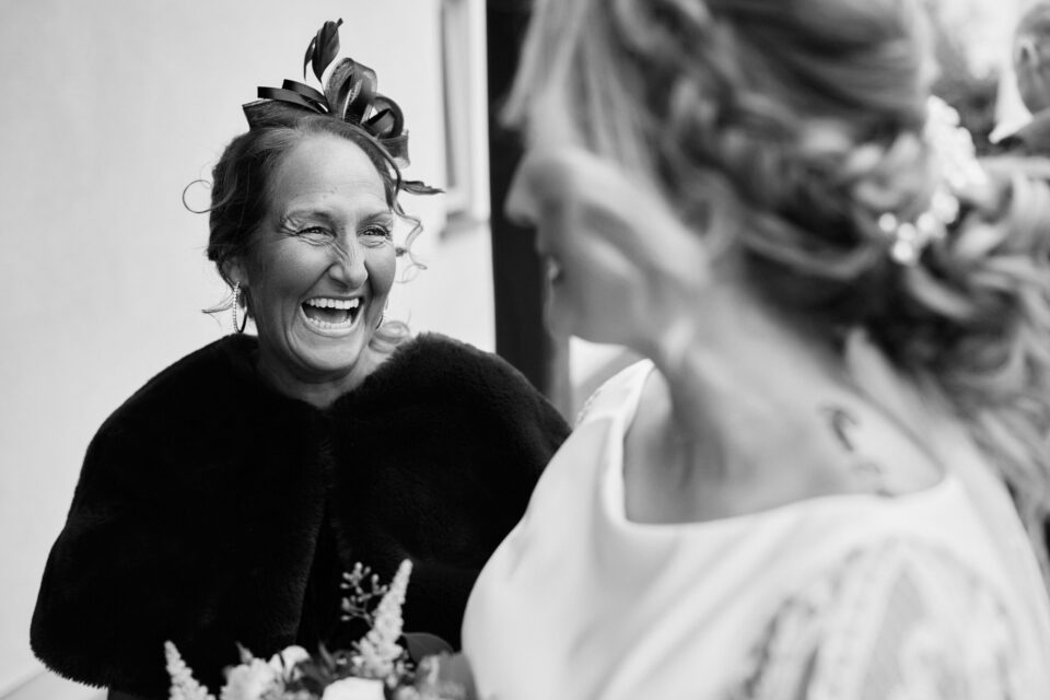 A black and white picture of a bride sharing a laugh with her mom.