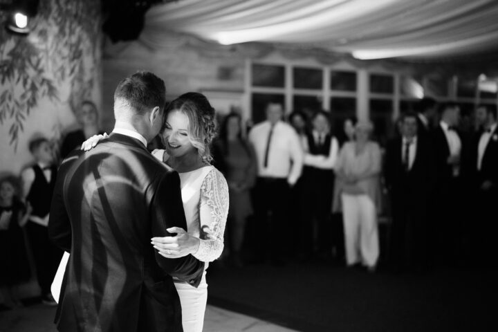 A couple dances for the first time at their wedding party with all their friends and family around, in a beautifully decorated tent.