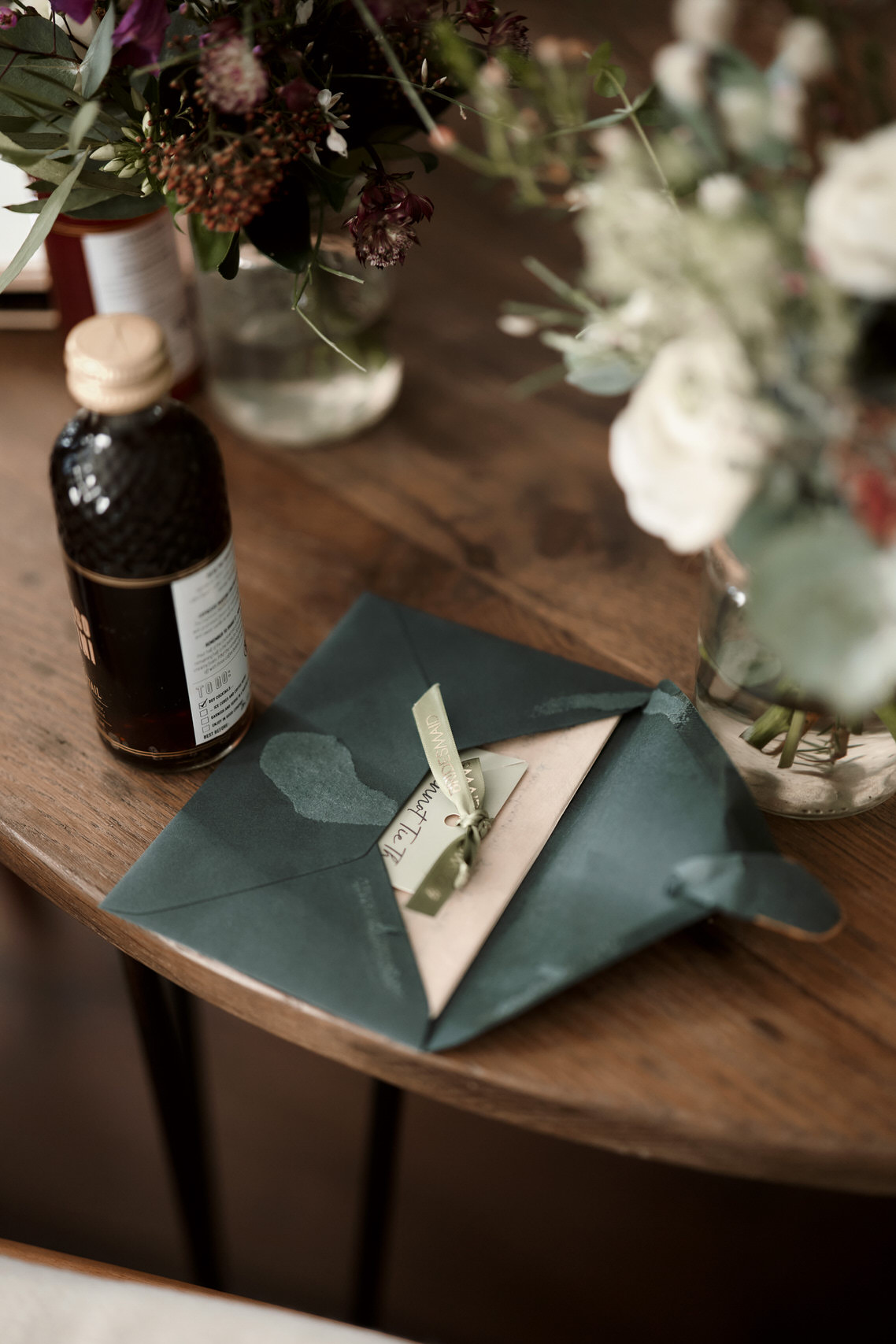 A green envelope tied with a ribbon sits beside a bottle of fluid.