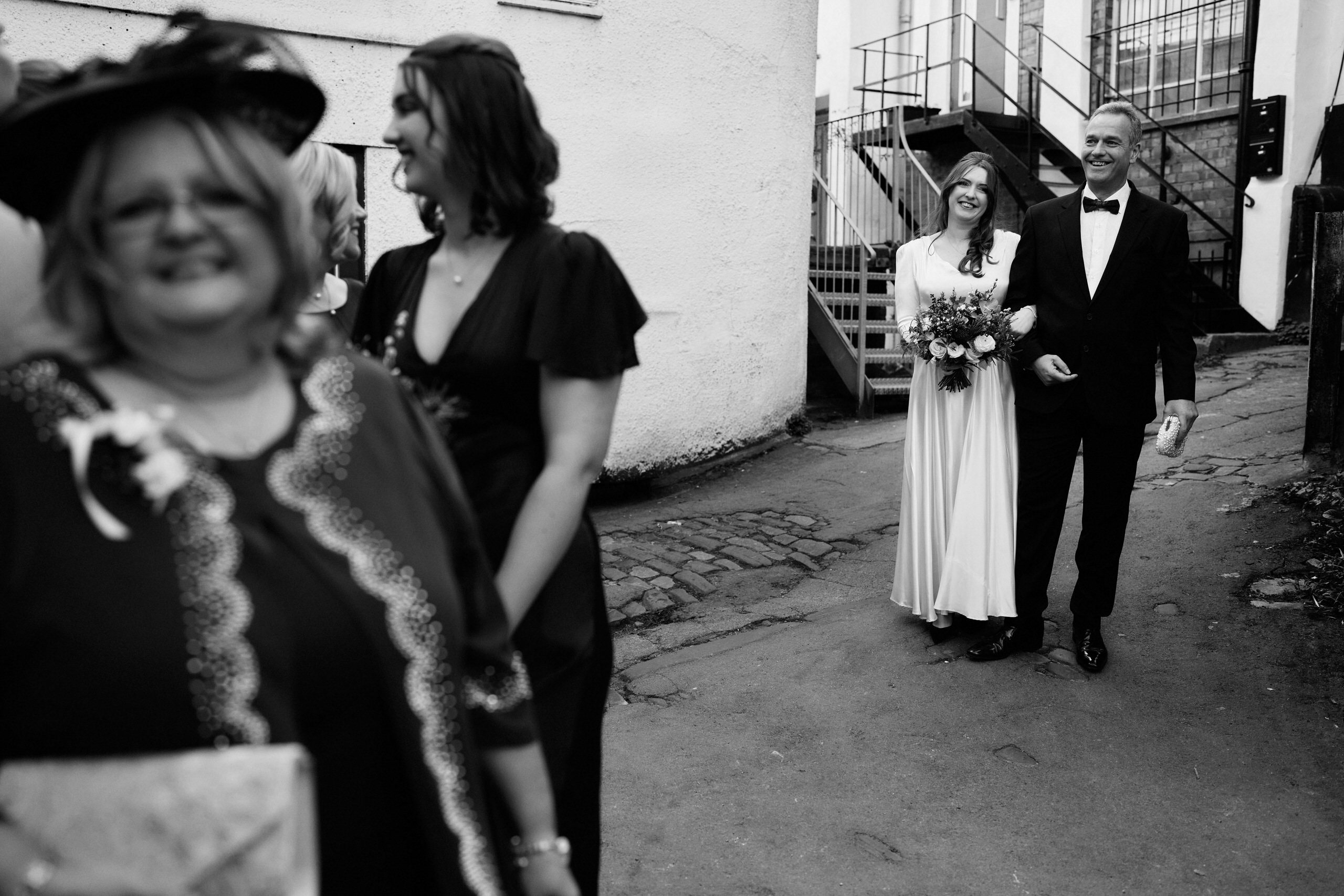 A black and white picture of a newly married couple walking down a lane.