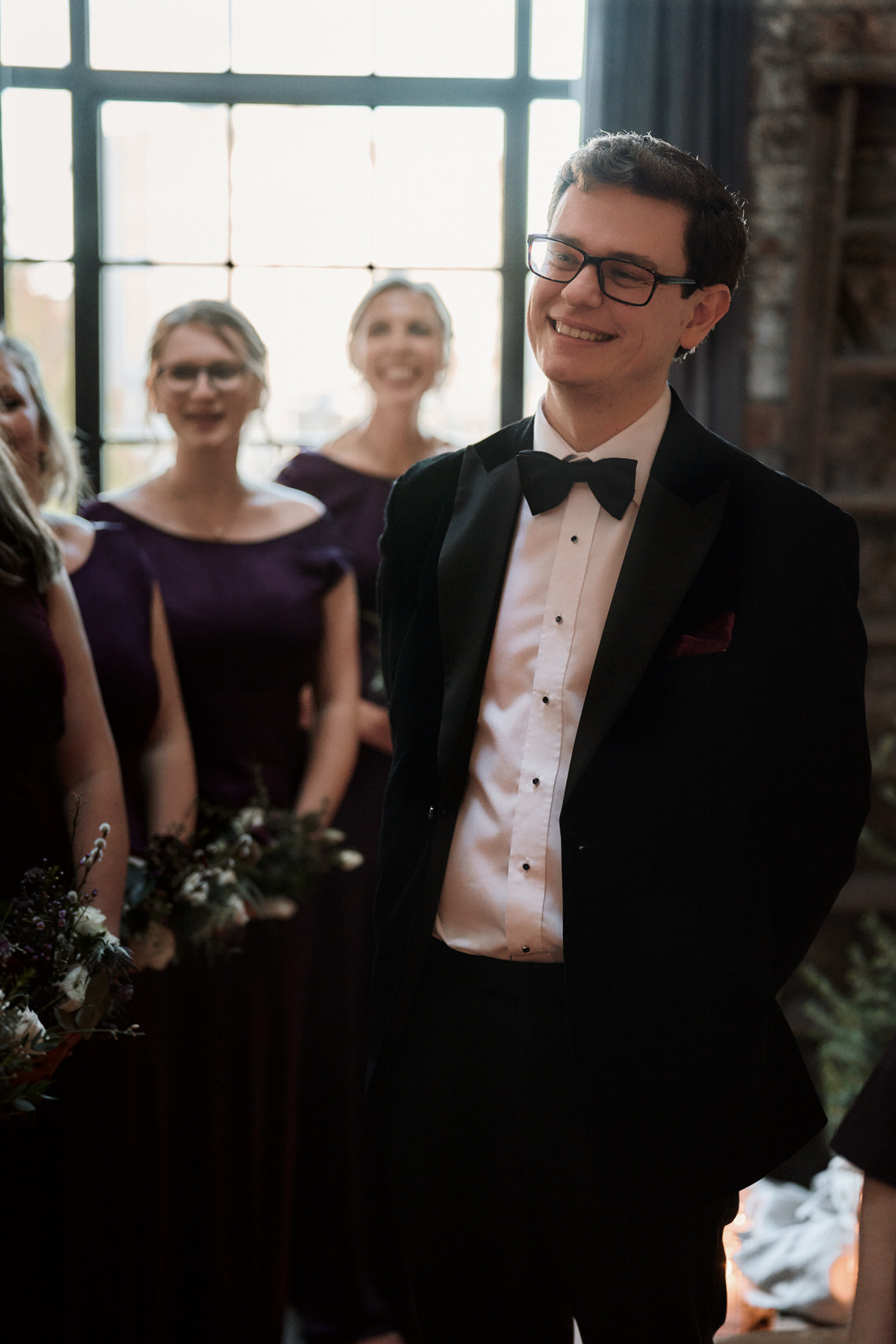 A guy in a suit is grinning at his bride's friends.