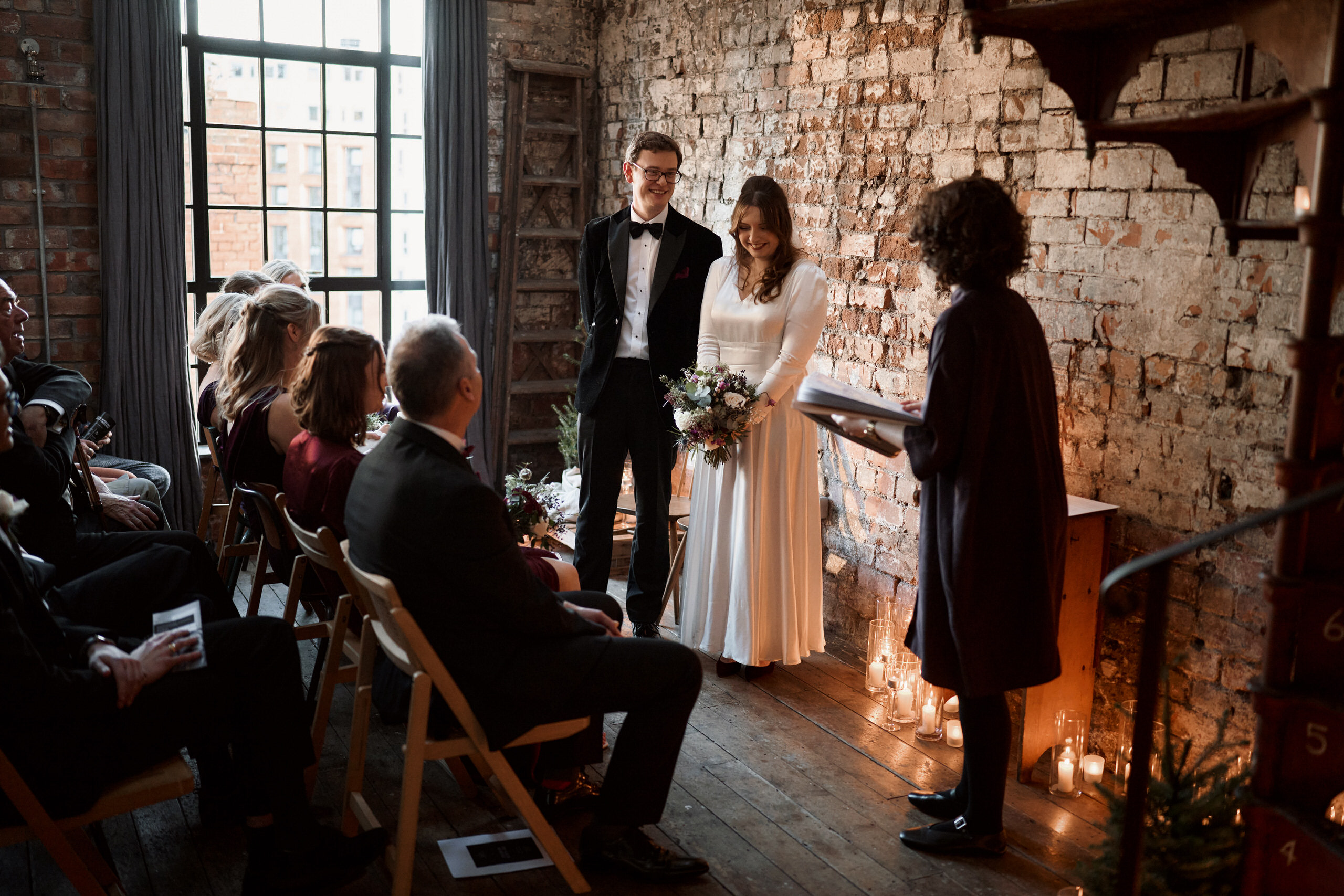 A couple is standing in front of a brick wall while they're getting married.