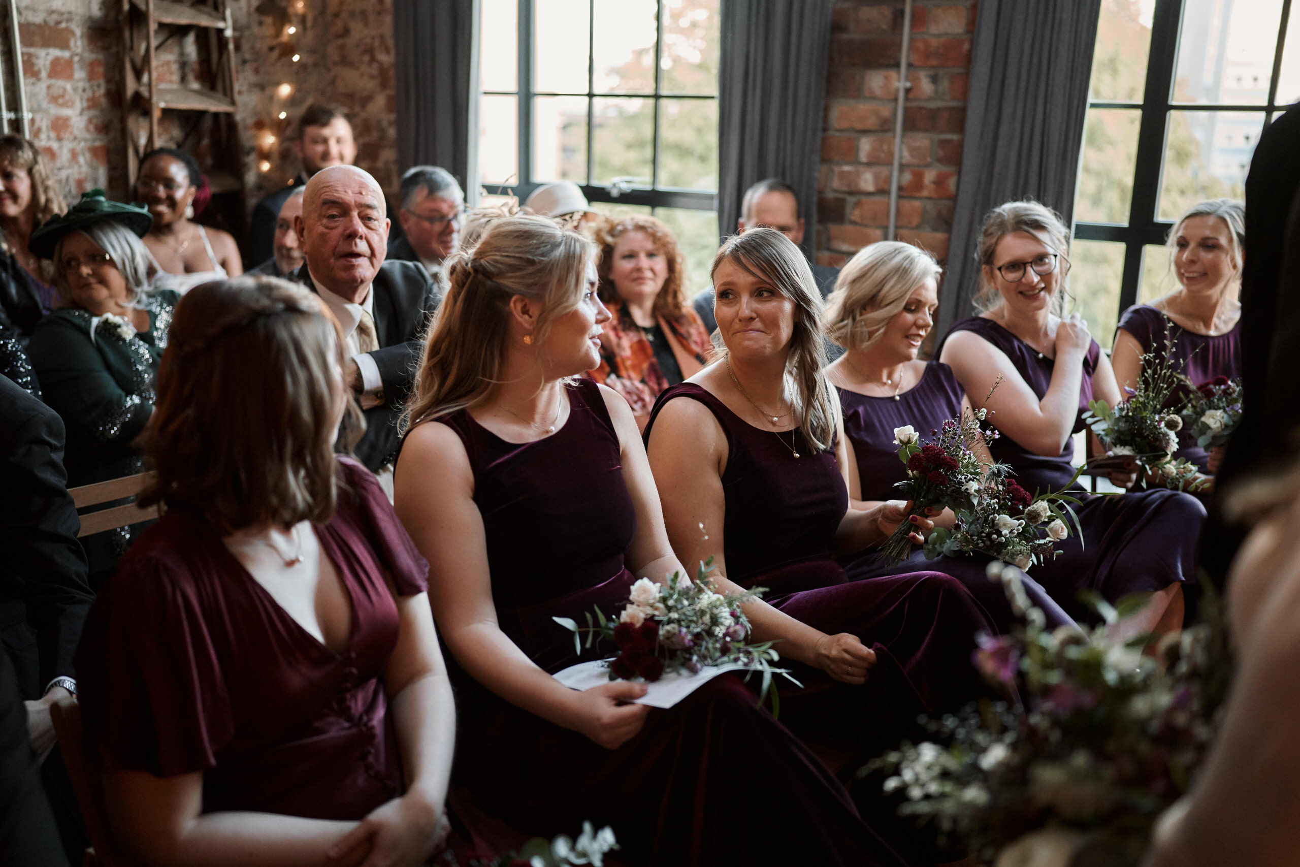 A bride and her friends are seated at a wedding ceremony.