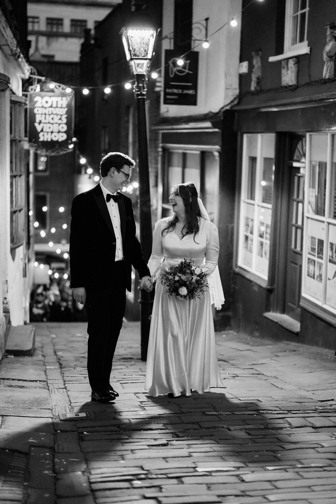 A couple just married is strolling down a street with cobblestones.