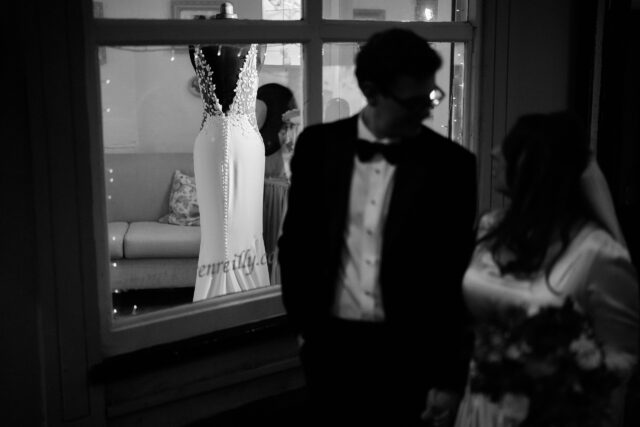 A couple checking out a wedding dress displayed in a store window.