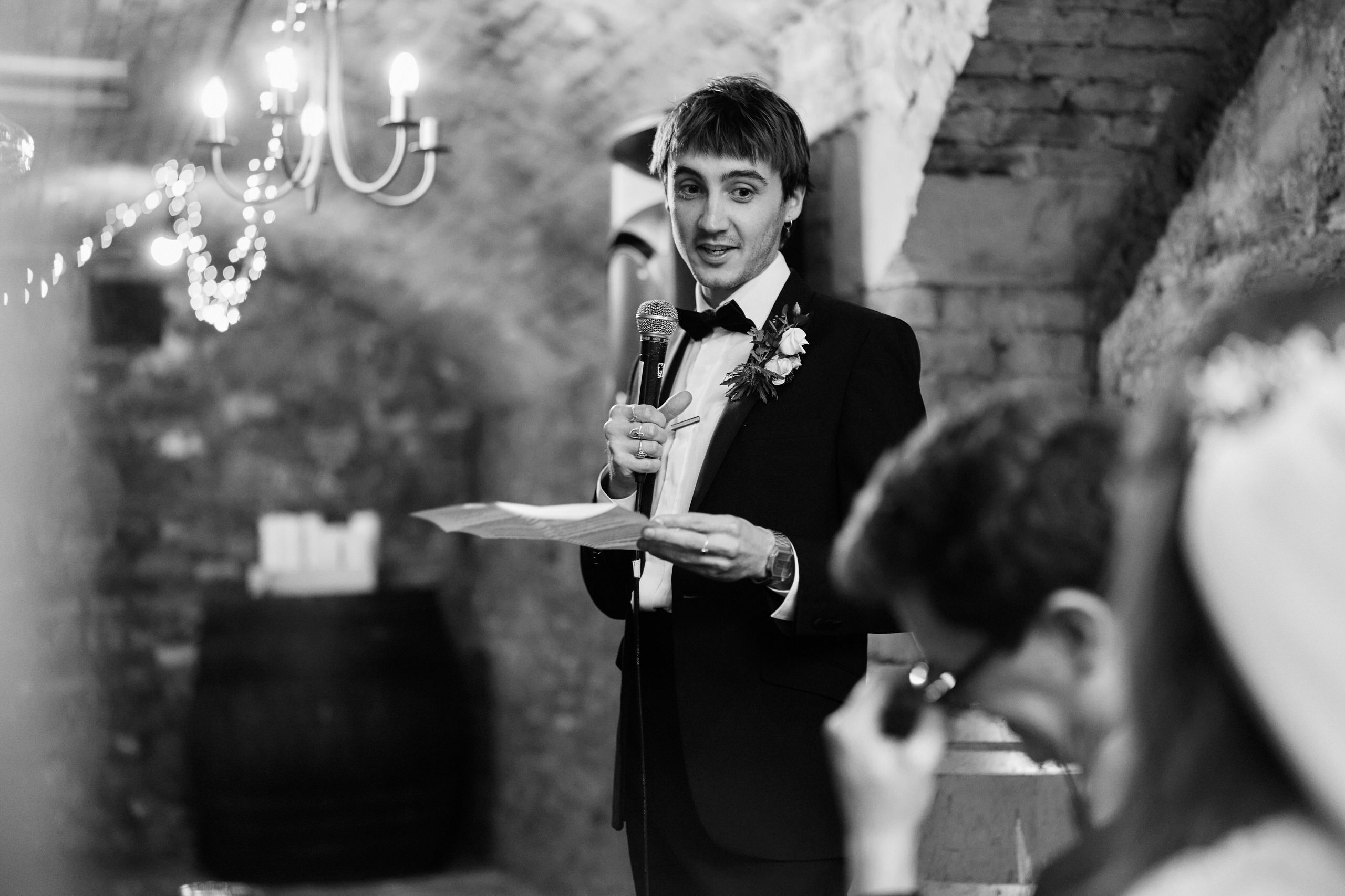 A guy in a fancy suit is talking at a wedding.