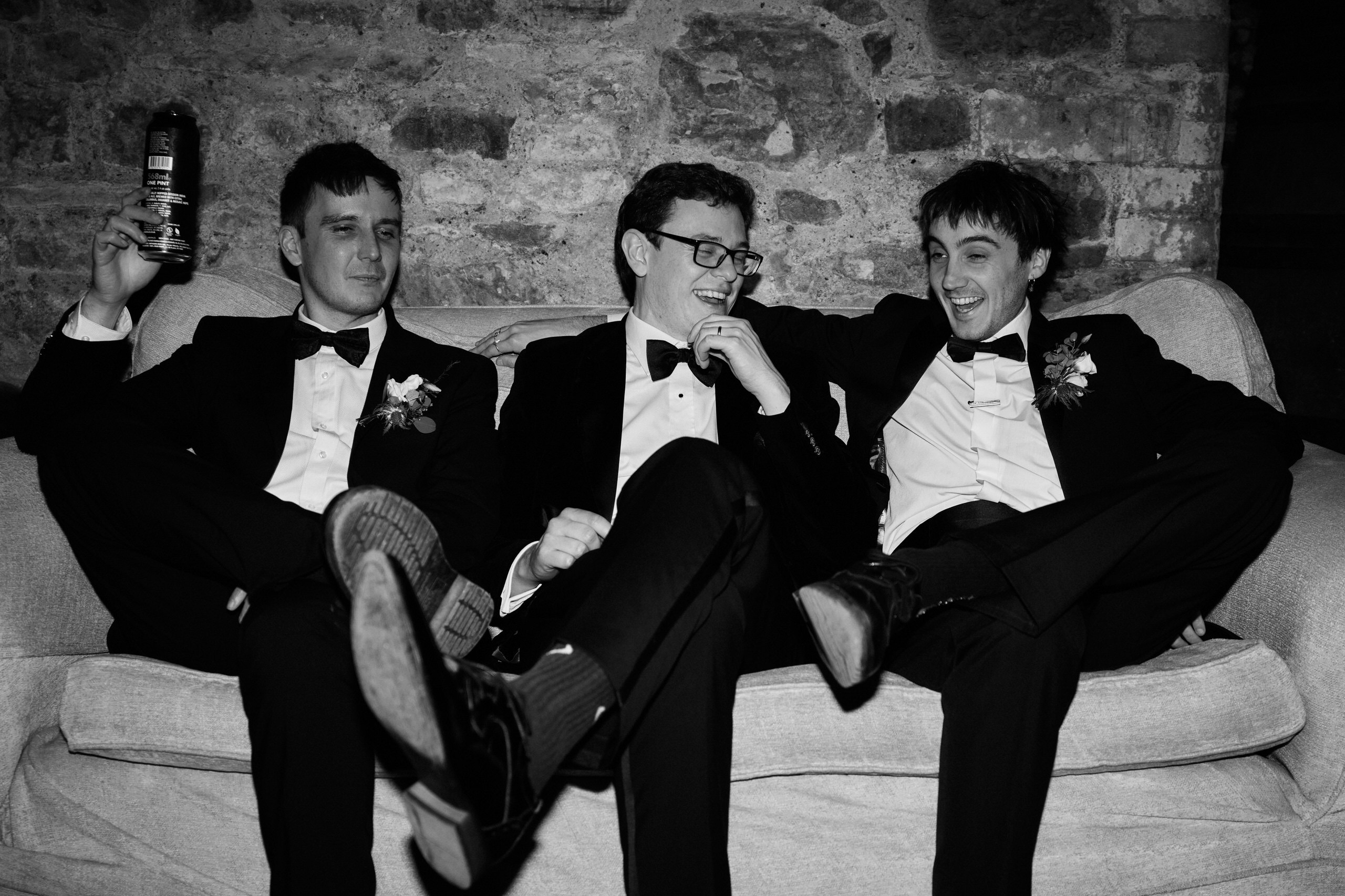 Three guys in suits are sitting on a sofa.