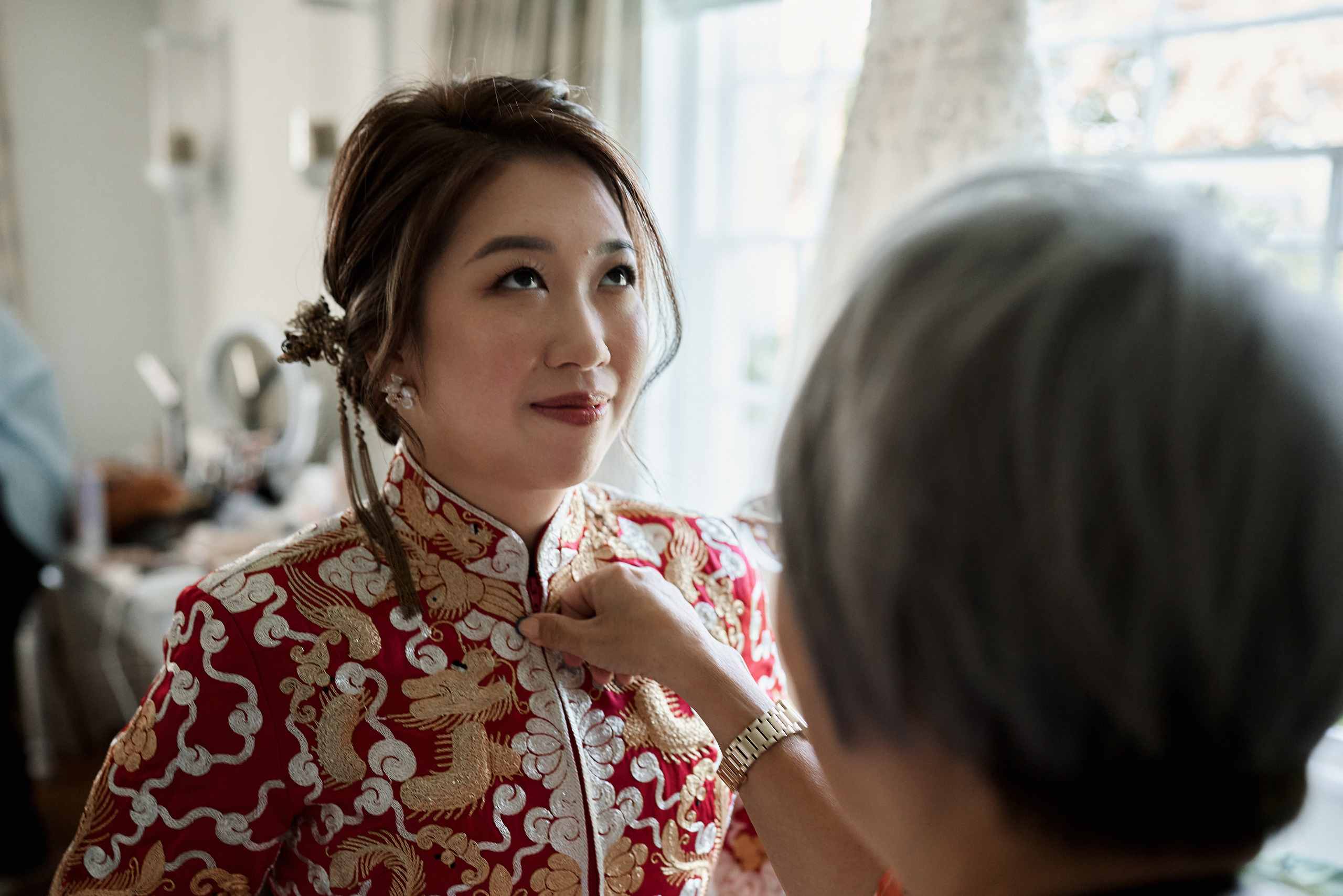 A lady in a red Chinese outfit is having her hair styled.
