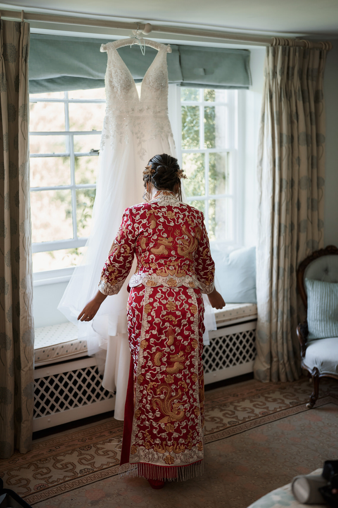 A lady in a Chinese outfit is checking out her bridal gown.