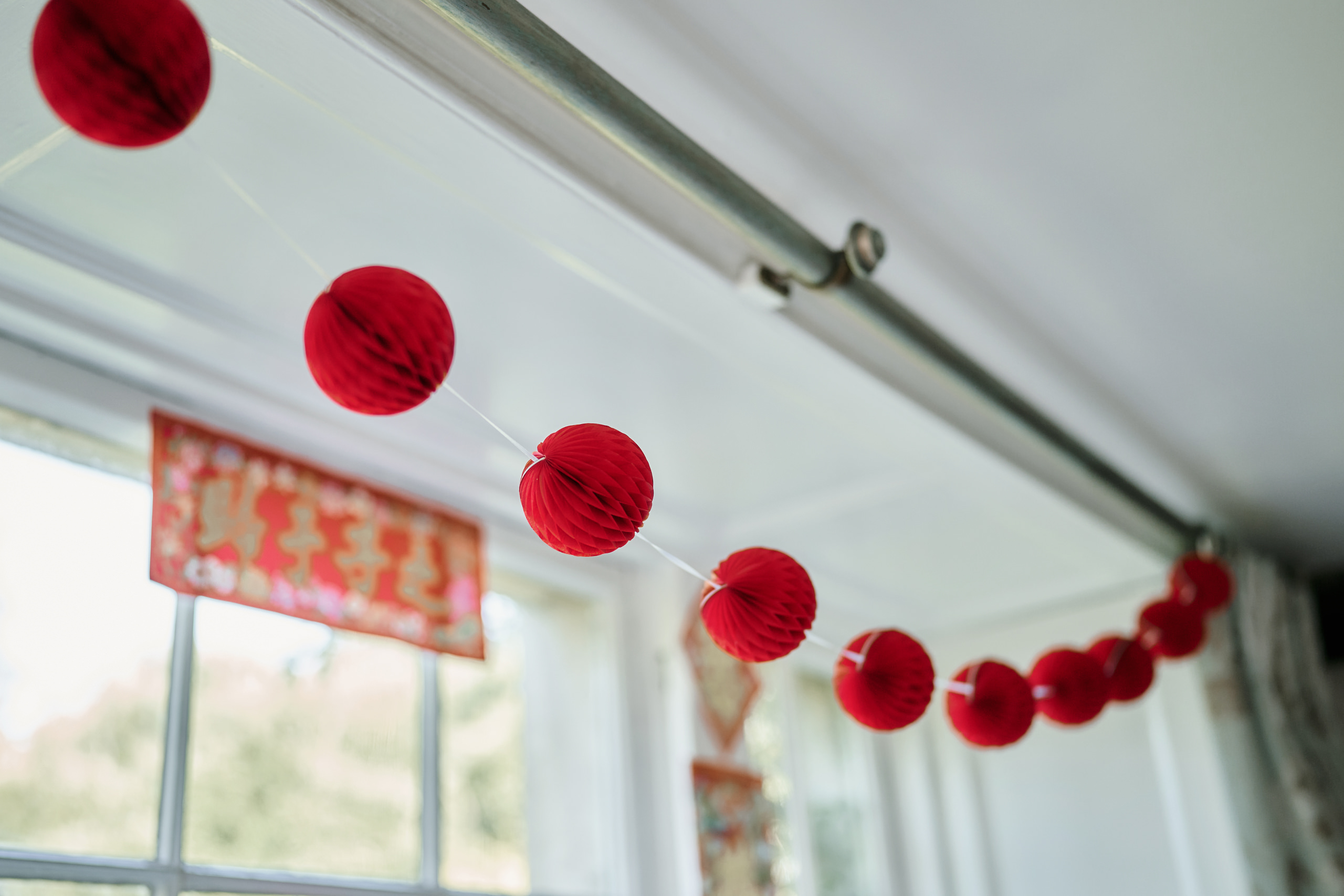 There's a string of red paper decorations hanging from a window.