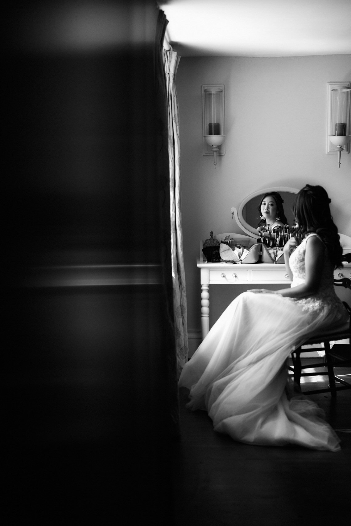 A bride is preparing herself in front of a mirror.