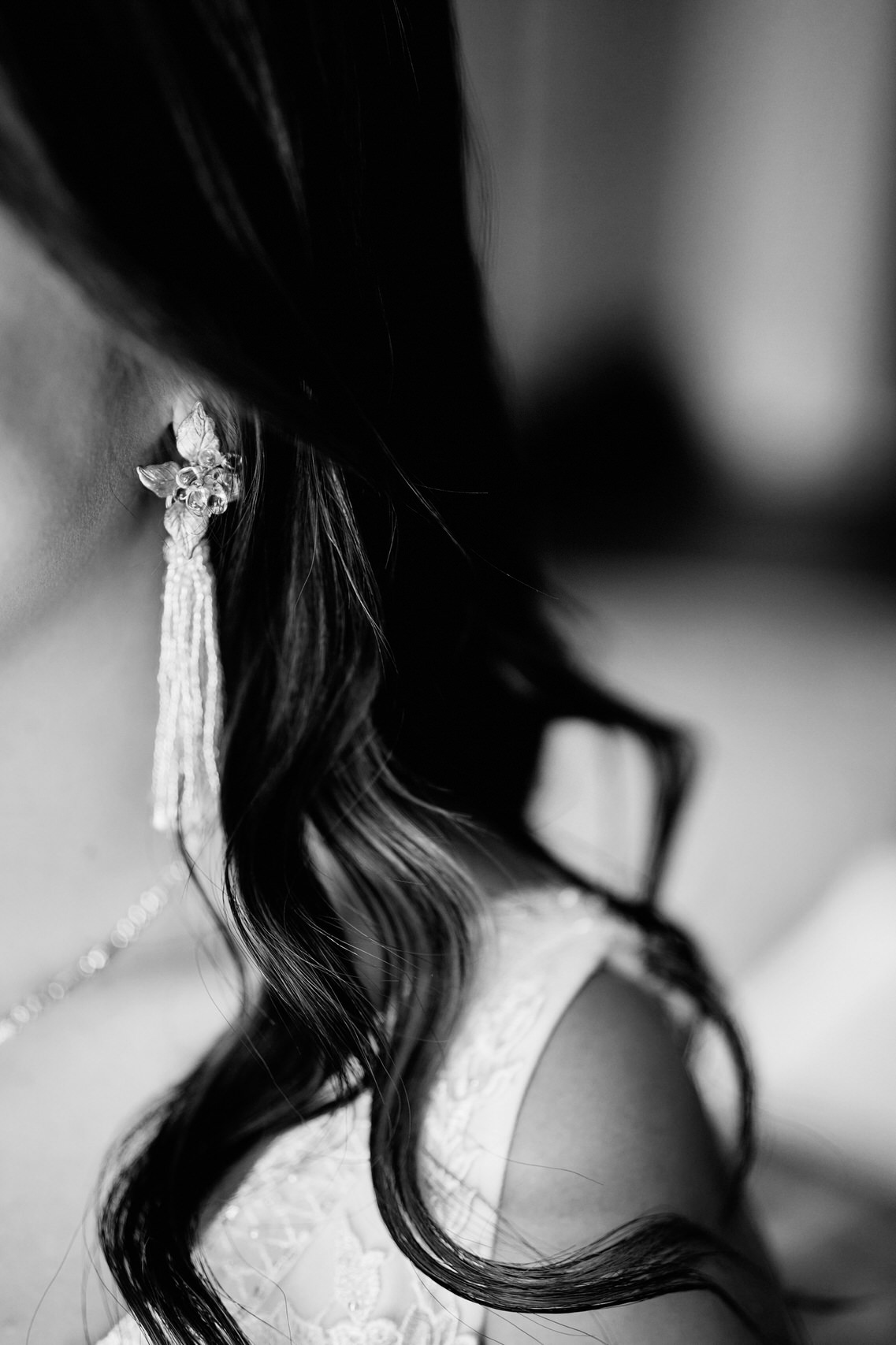 A picture in black and white of a bride with earrings on.